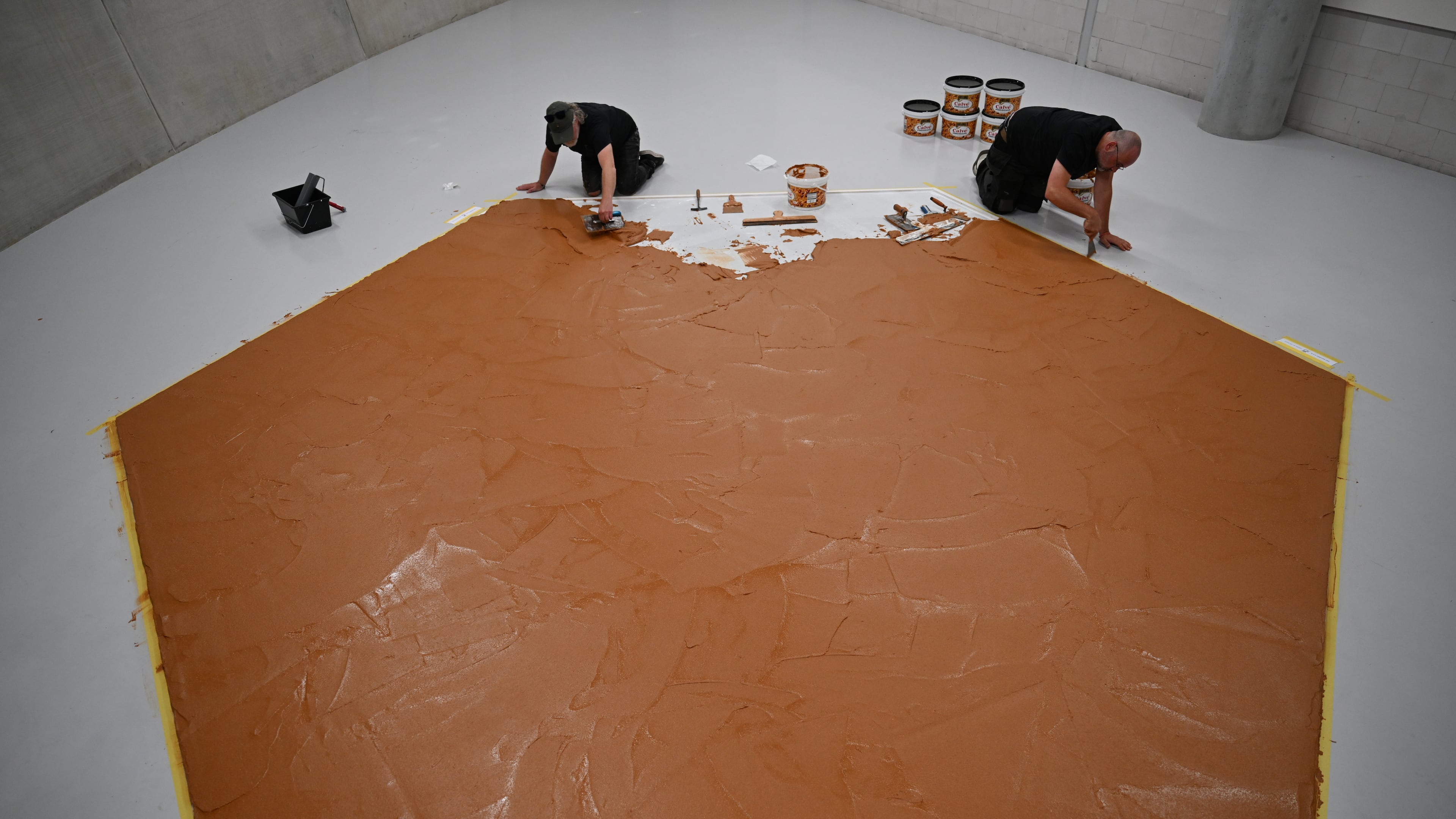 Workers spread peanut butter on a floor to recreate the "Peanut Butter Floor" artwork in tribute to Dutch artist Wim T. Schippers at the Museum Boijmans Van Beuningen in Rotterdam, Netherlands, Friday, July 3, 2026. (AP Photo/Mouneb Taim)