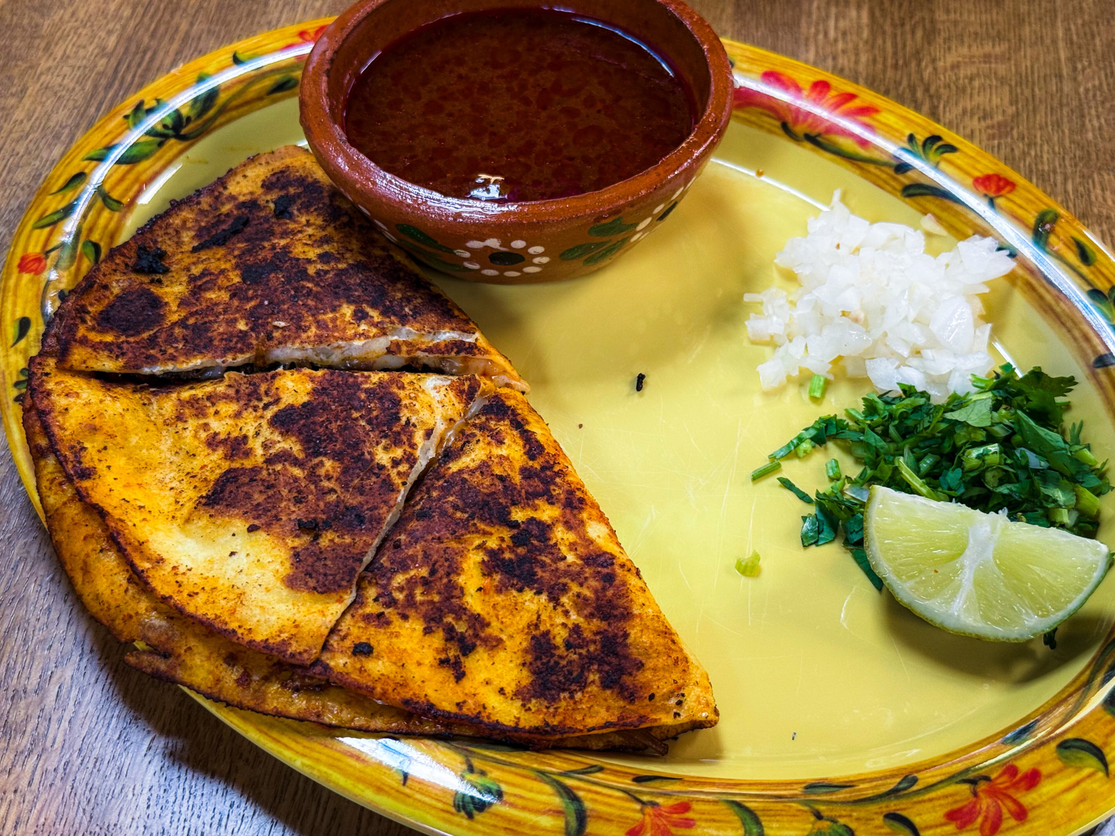 The quesabirria at Cocina de la Tia stands out, with its tender beef, plenty of cheese and a side of consommé for dipping. (Henri Hollis/henri.hollis@ajc.com)