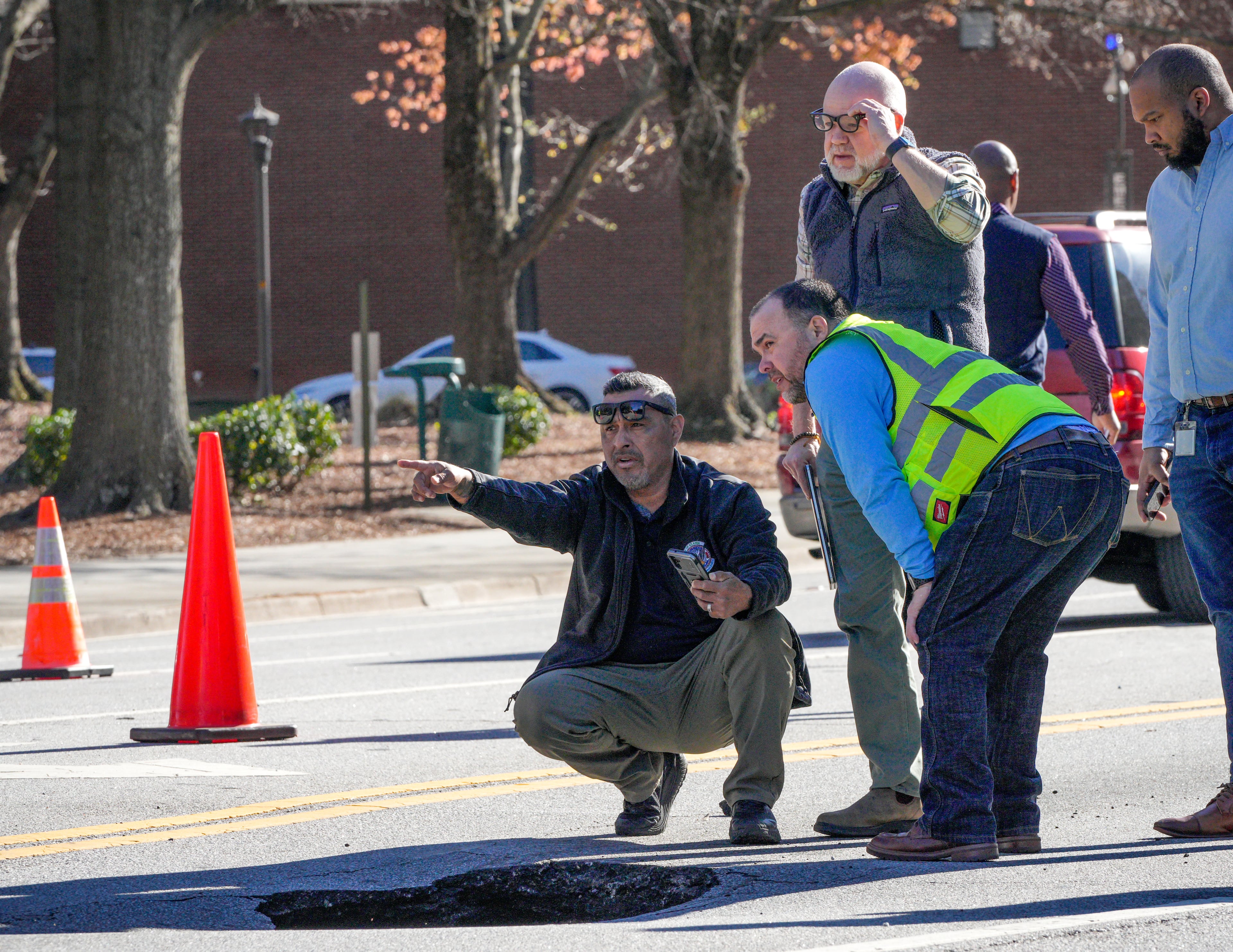 An Atlanta Watershed employee (left) speaks with workers from Coca-Cola headquarters after a large hole opened up on North Avenue.