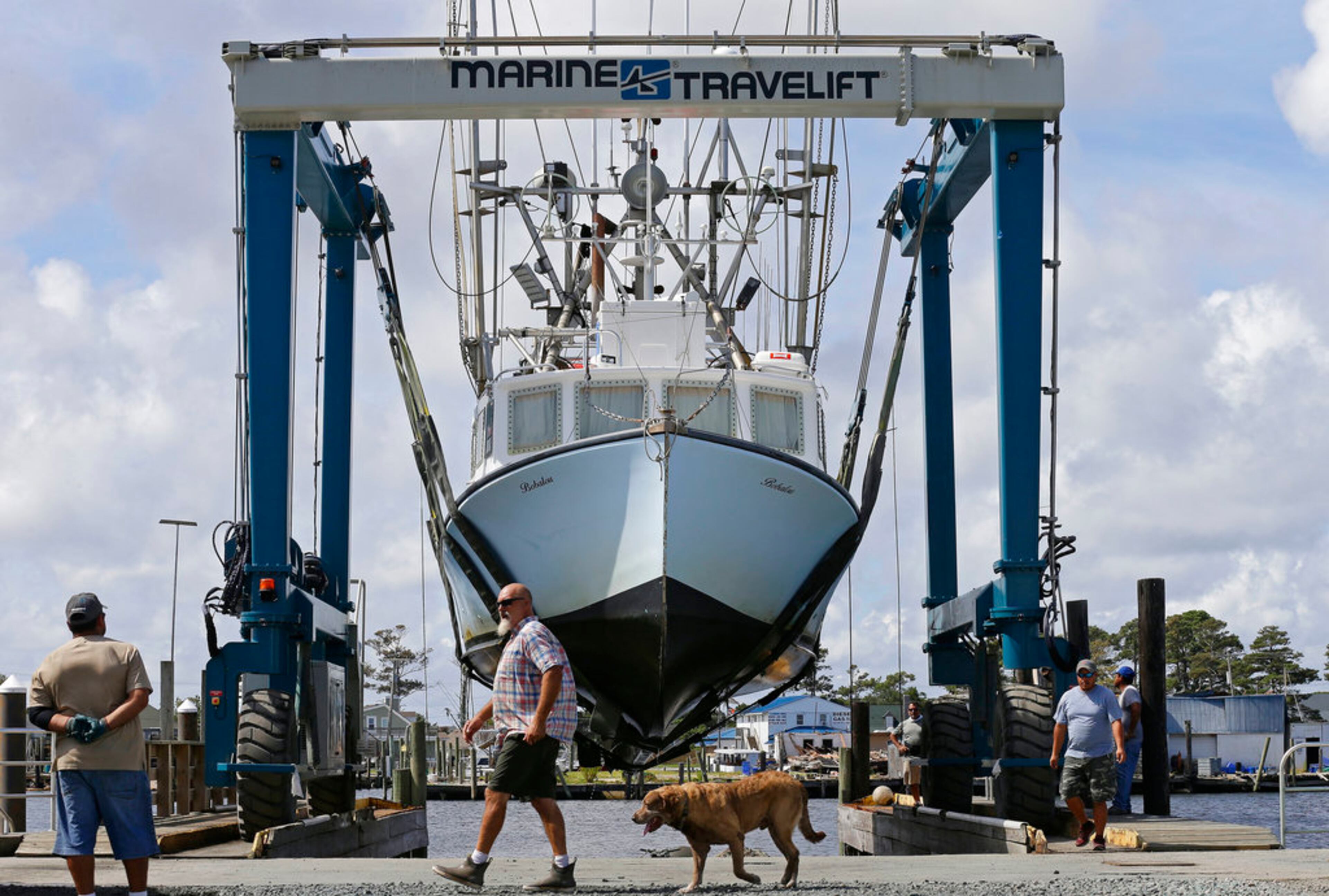 Workers take boats out of the water in Wanchese Harbor as Hurricane Florence approaches the coast of the Carolinas on Wednesday, Sept. 12, 2018, in Wanchese, N.C. The National Weather Service says Hurricane Florence "will likely be the storm of a lifetime for portions of the Carolina coast." (AP Photo/Gerry Broome)