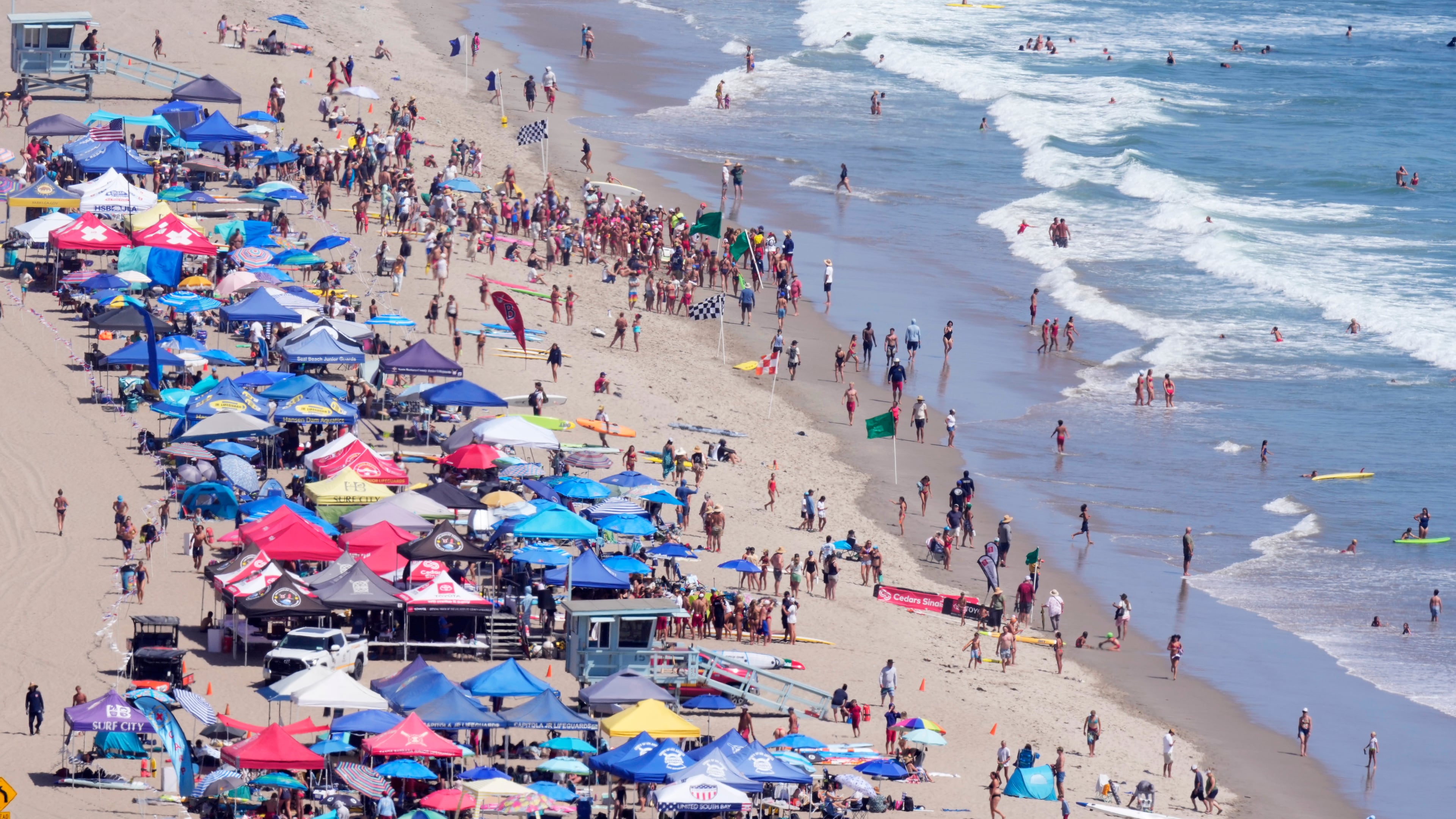 Beach goers watch during the the 46th Annual California Surf Lifesaving Championships on Will Rogers State Beach Friday, July 24, 2026, in the Pacific Palisades section of Los Angeles. (AP Photo/Mark J. Terrill)