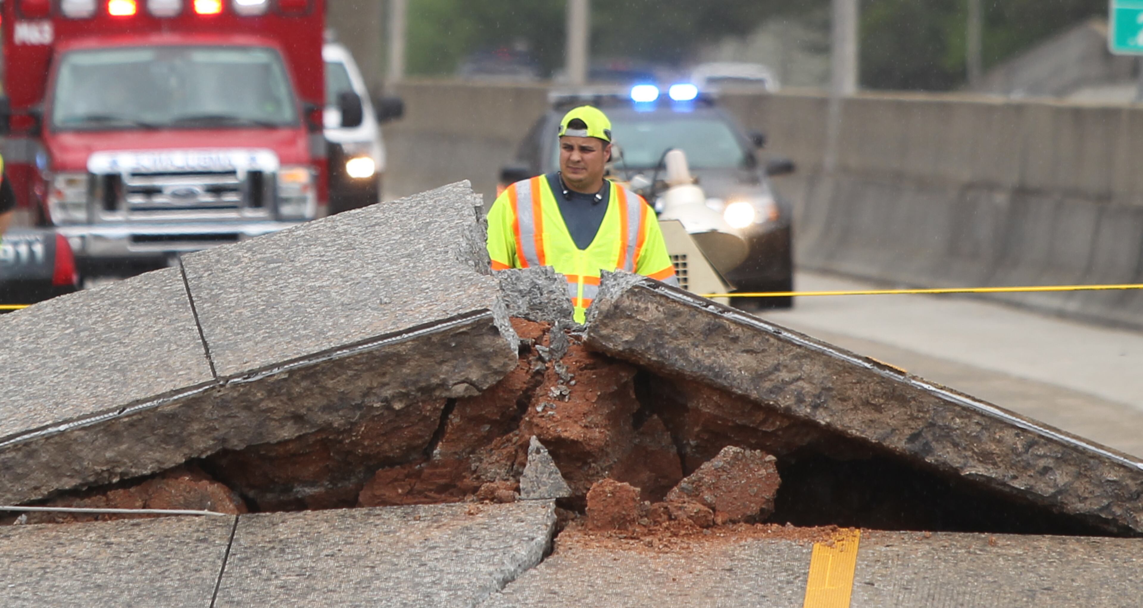 April 17, 2017, Atlanta, Georgia - A crew member glances through the large rift in I-20 WB after the road buckled that morning in Atlanta, Georgia, on April 17, 2017. On the morning of April 17th a section of I-20 WB near the Gresham Road exit buckled. According to Dekalb County Fire Department PIO Eric Jackson there were private contractors working on a gas pipe running underneath the interstate. The private contractors were filling the pipe with cement when pressure started building up. According to Jackson the buckle acted as a pressure release valve. According to WSB-TV, they were told the rise of concrete was gradual and not sudden. In addition to all west bound lanes being closed while crews assess the situation, a motorcyclist may have crashed after running into the buckle, the driver of the motorcycle was taken to a local area hospital. (HENRY TAYLOR / HENRY.TAYLOR@AJC.COM)