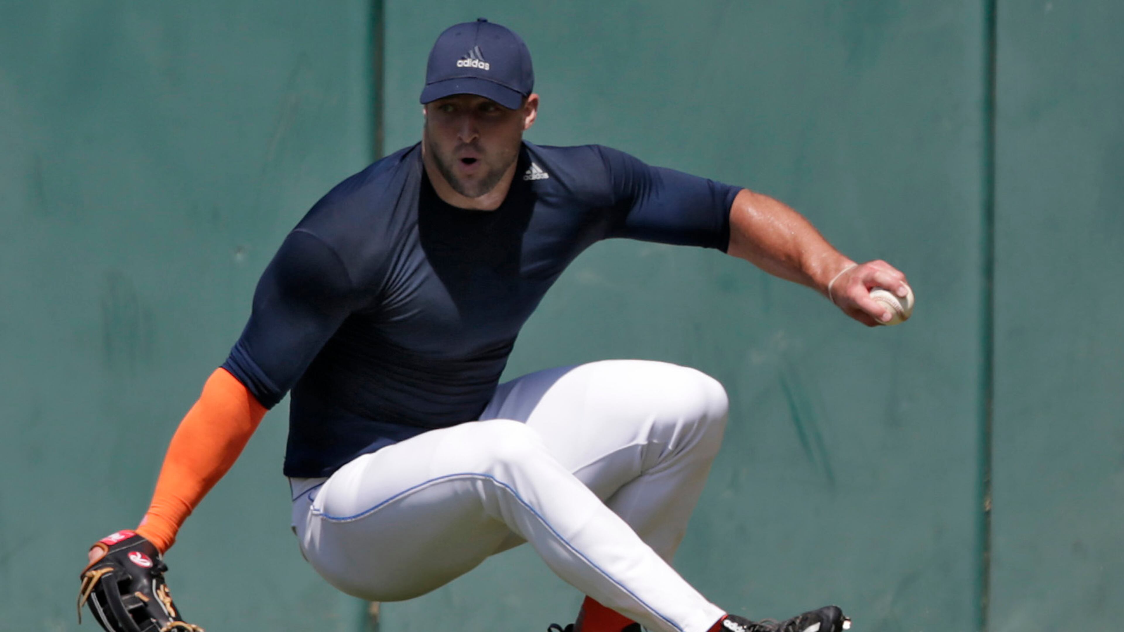 Former NFL quarterback Tim Tebow loses his footing as he fields a ball during outfield drills at USC's Dedeaux Field in Los Angeles during a private baseball tryout. (Robert Gauthier / Los Angeles Times)