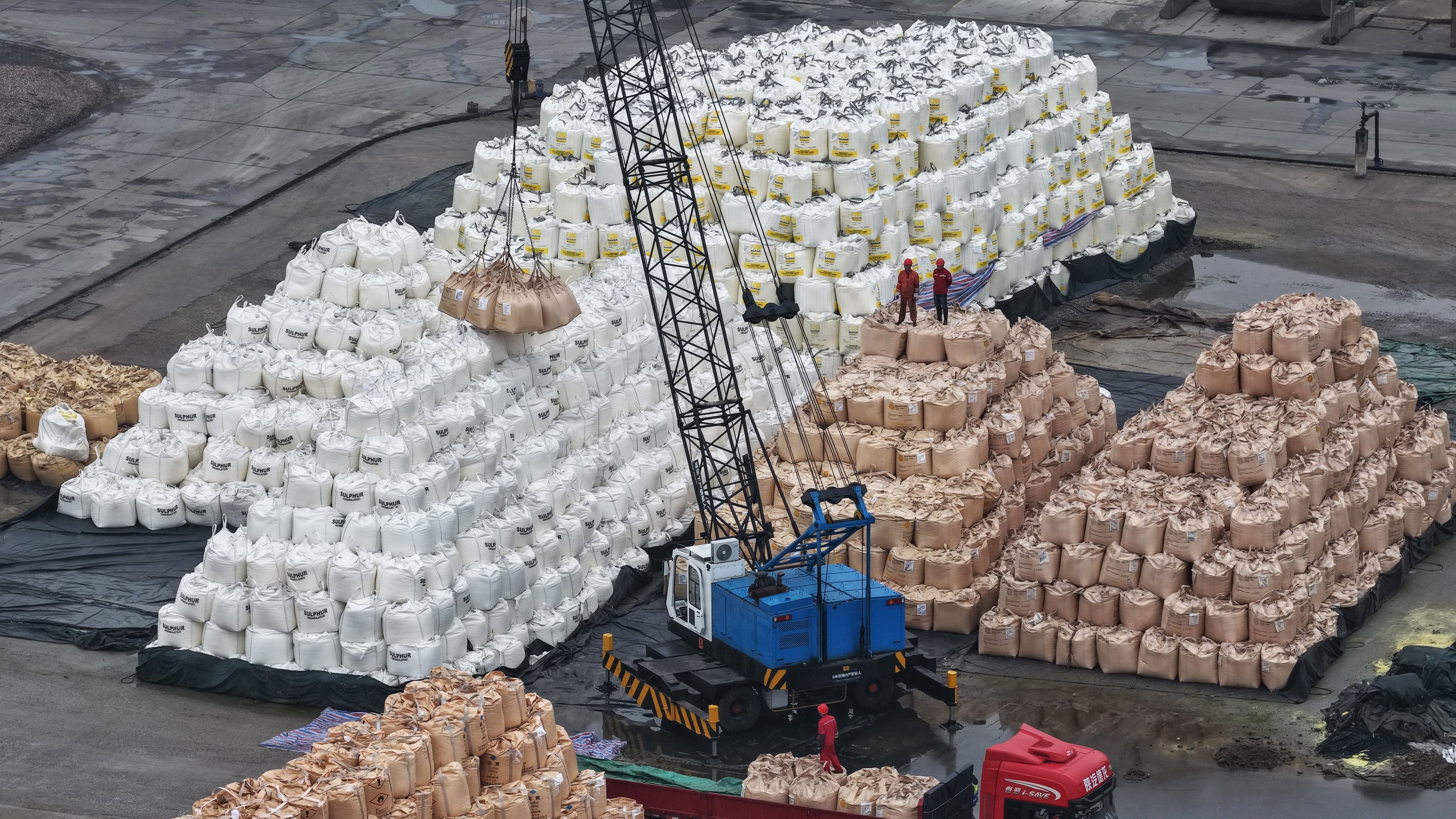 Workers transfer bags of imported solid sulfur onto a truck in a port in Nanjing in eastern China's Jiangsu province, Tuesday, April 14, 2026. (Chinatopix Via AP) CHINA OUT