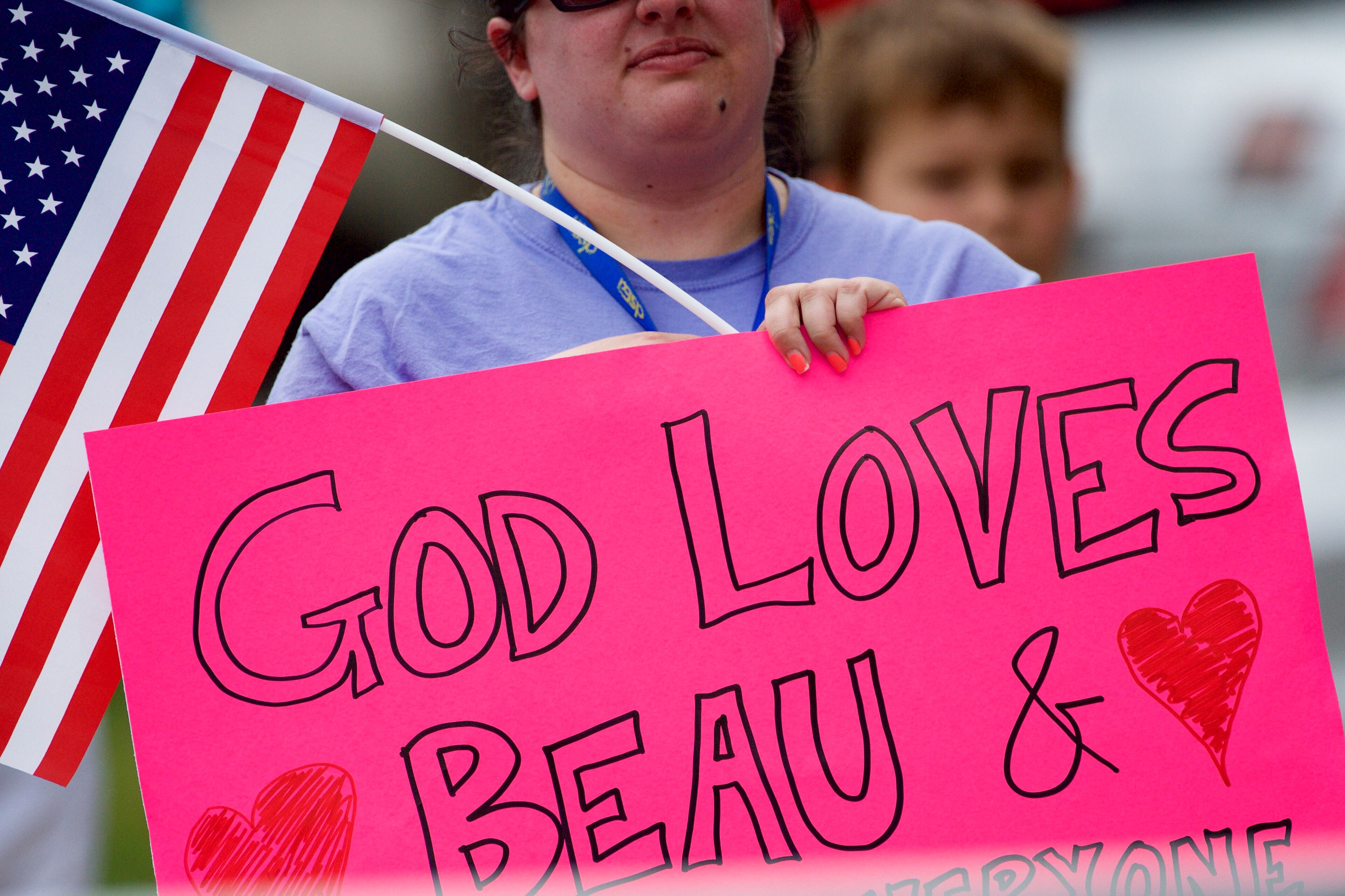 WILMINGTON, DE - JUNE 6: A woman holding a "God Loves Beau and Joe (Biden)" reacts as the hearse and Biden family arrive for a mass of Christian burial at St. Anthony of Padua Church for former Delaware Attorney General Beau Biden, on June 6, 2015 in Wilmington, Delaware. U.S. President Barack Obama is expected to deliver a eulogy for the son of Vice President Joe Biden after he died at 46 following a two-year battle with brain cancer. (Photo by Mark Makela/Getty Images)