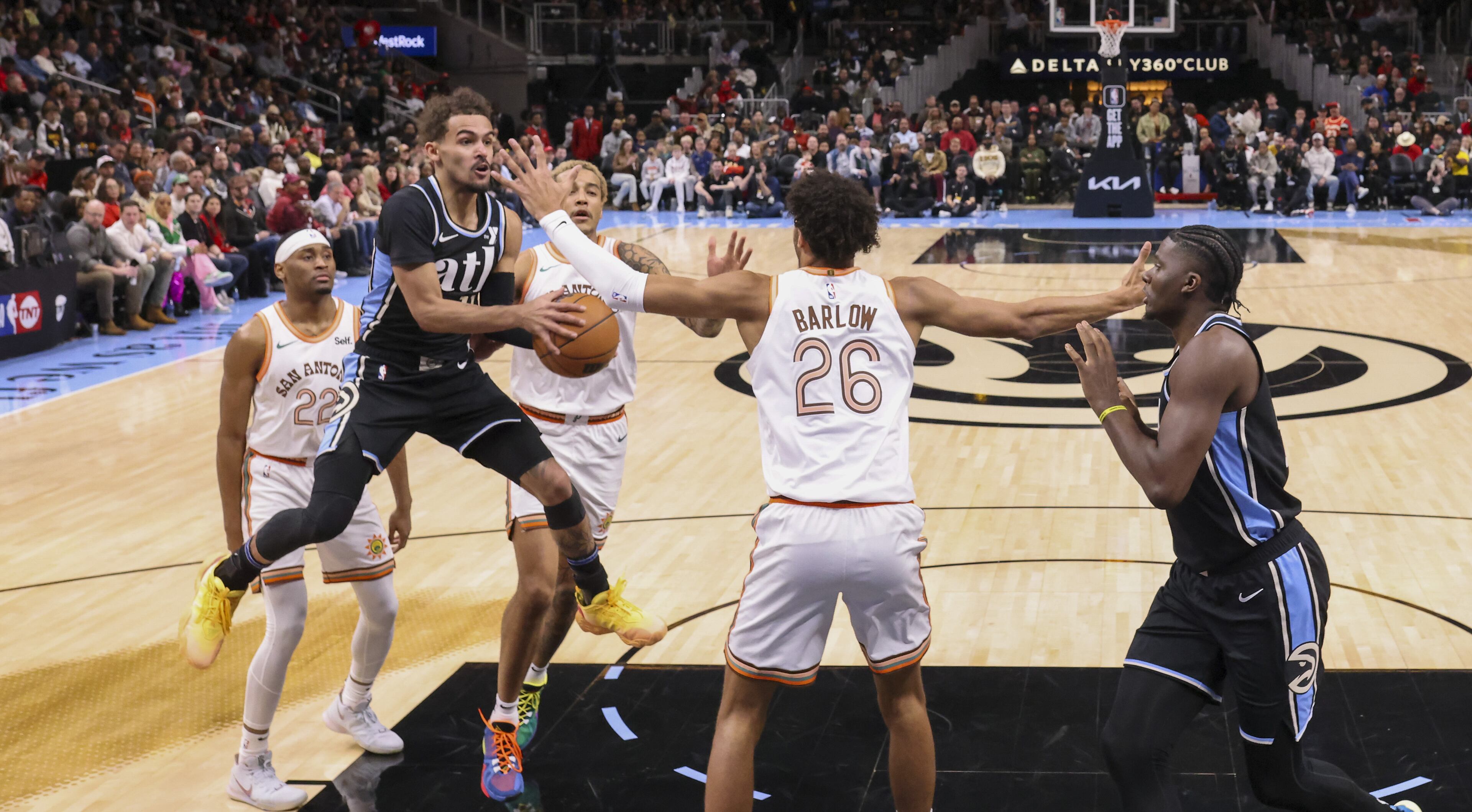 Hawks guard Trae Young (11) attempts a pass against Spurs forward Dominick Barlow (26) to Hawks center Clint Capela (15) during the first half of the Hawks’ annual MLK Day game at State Farm Arena, Monday, January 15, 2024, in Atlanta. The Hawks won 109-99. (Jason Getz / Jason.Getz@ajc.com)