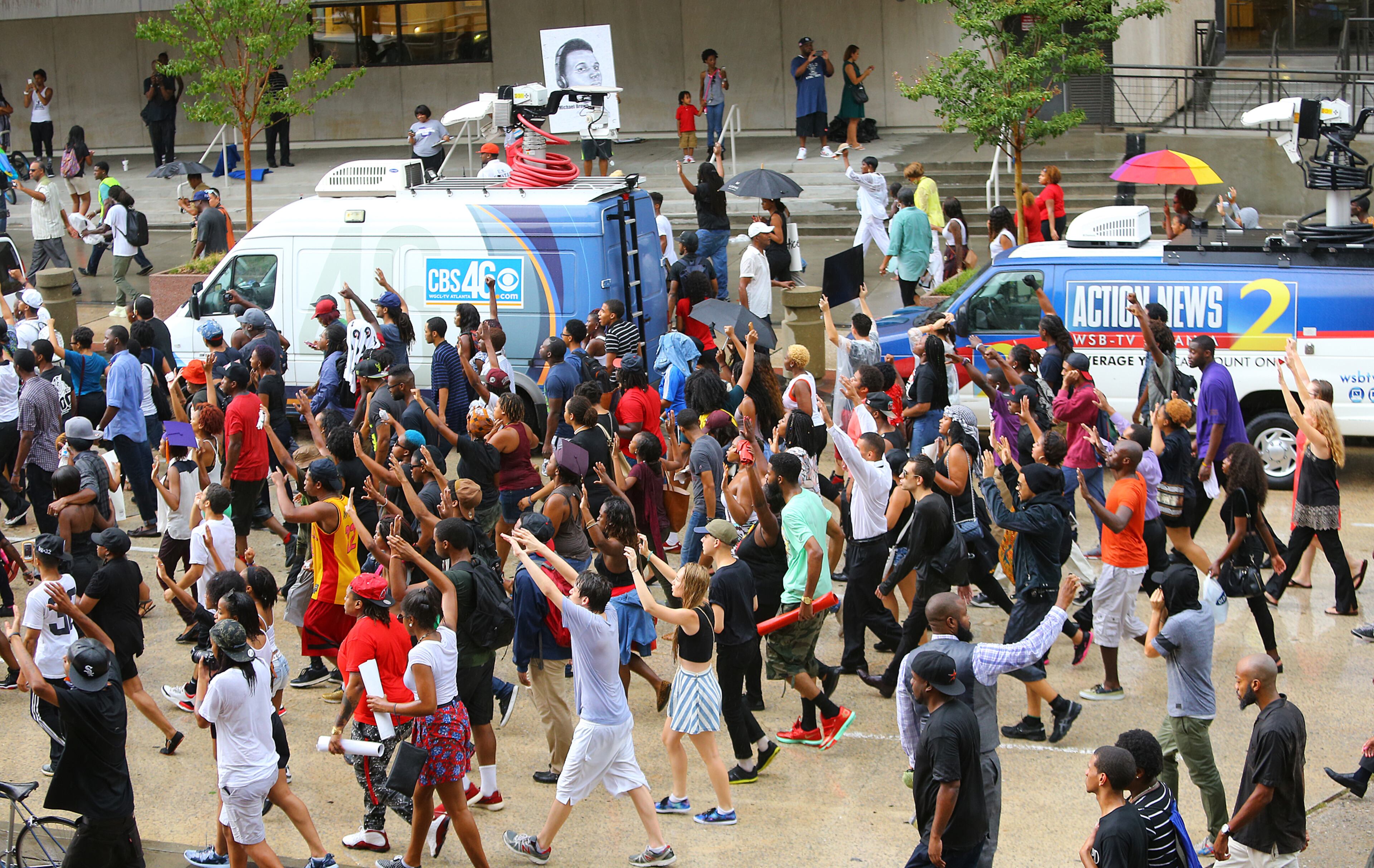081814 Atlanta: Protesters march past news vehicles during a rally for Mike Brown and Ferguson outside the CNN Center on Monday, August 18, 2014, in Atlanta. CURTIS COMPTON / CCOMPTON@AJC.COM