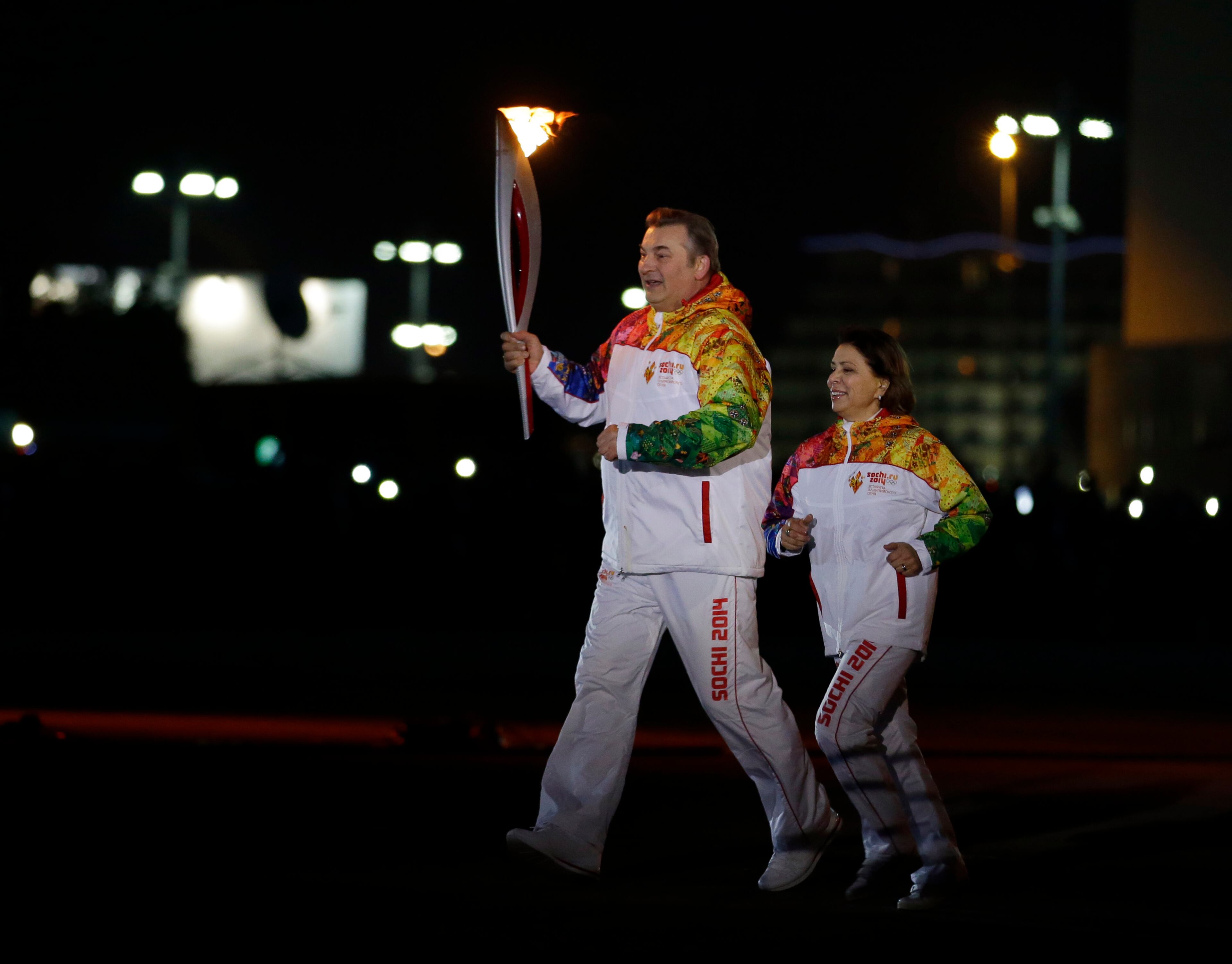 Irina Rodnina and Vladislav Tretyak run before lighting the Olympic cauldron during the opening ceremony of the 2014 Winter Olympics in Sochi, Russia, Friday, Feb. 7, 2014. (AP Photo/Matt Slocum, Pool)