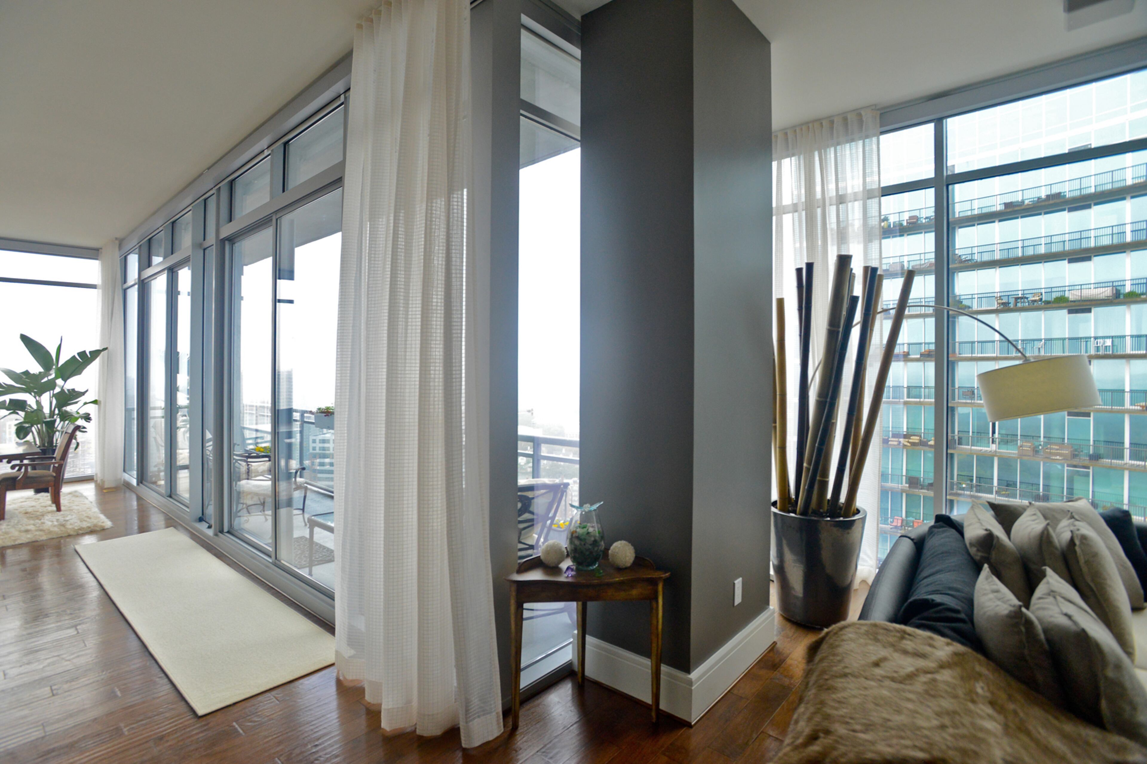 Long sheer curtains, by Motion Shading, dress up the high-rise space without detracting from the almost 360 degree views from the 36th-floor corner unit in Midtown.