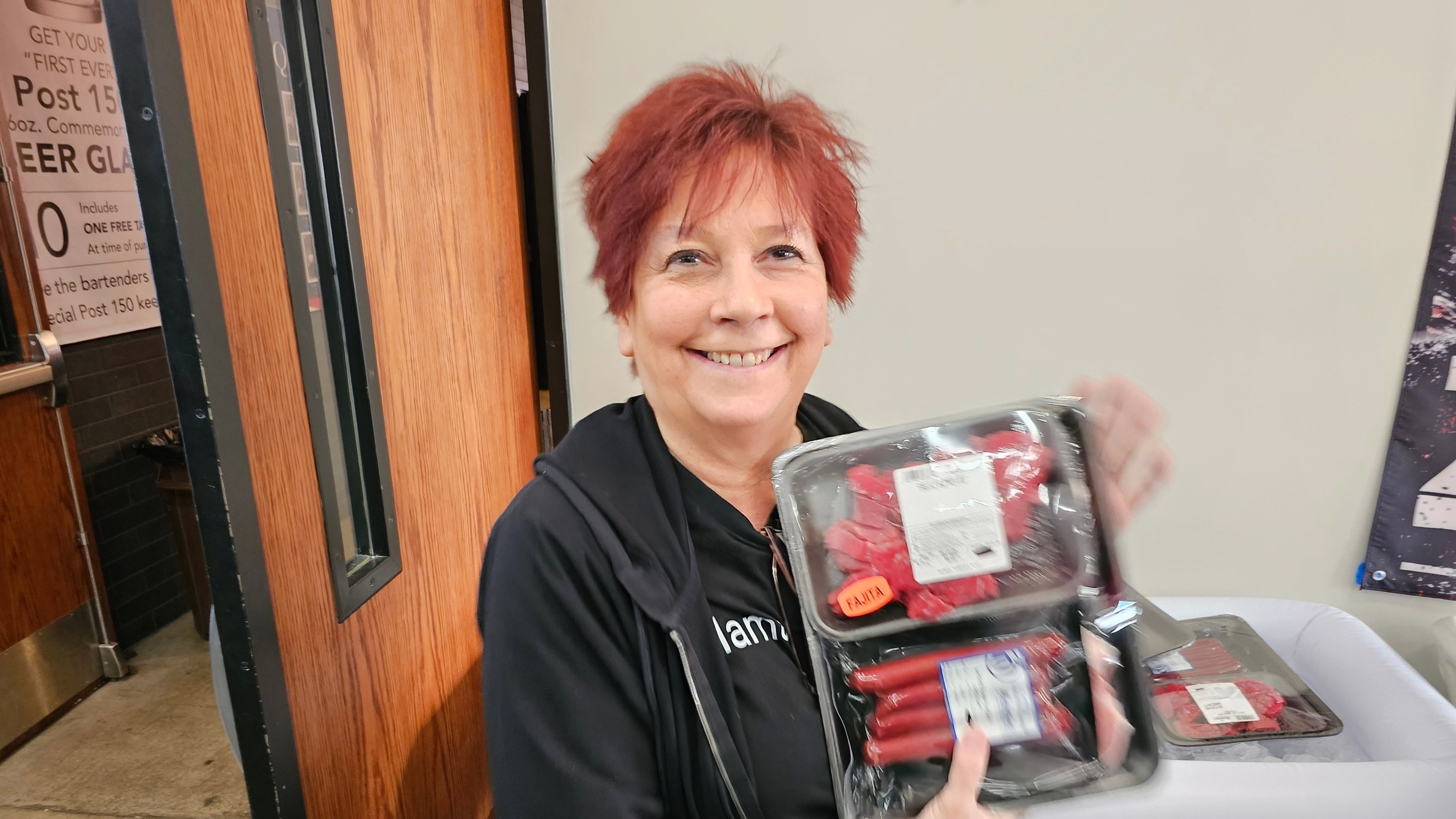 Andrea "Mama" Avaloz holds up the package of fajita meat, beef sticks and pork chops that she won in a meat raffle April 10, 2026, at American Legion Post 150 in Waconia, Minn. (AP Photo/Steve Karnowski)