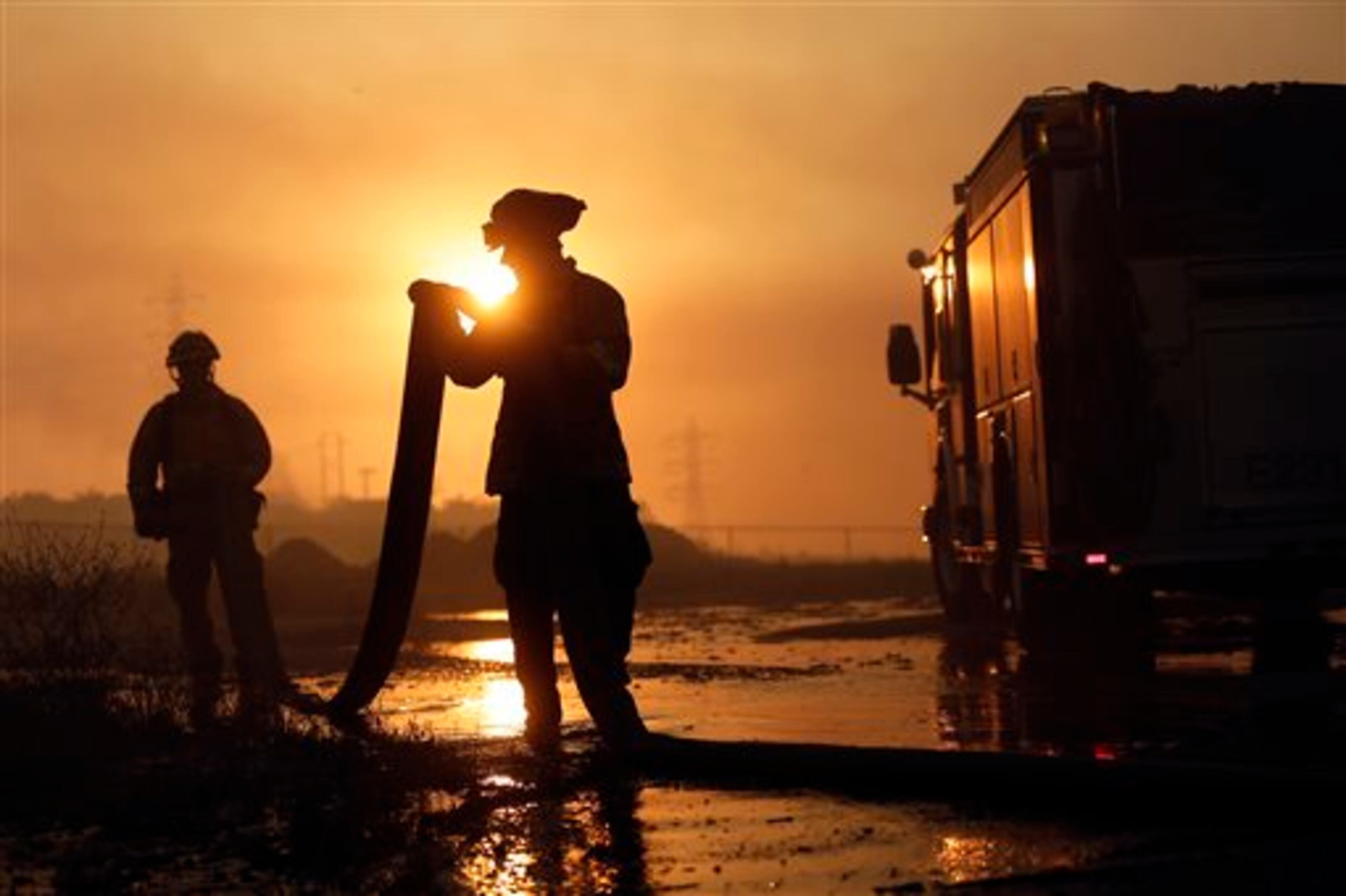 Del Mar firefighters roll up hose after a day fighting wildfires Wednesday, May 14, 2014, in Carlsbad, Calif. More wildfires broke out Wednesday in San Diego County, threatening homes in Carlsbad and forcing the evacuations of military housing and an elementary school at Camp Pendleton. (AP Photo)