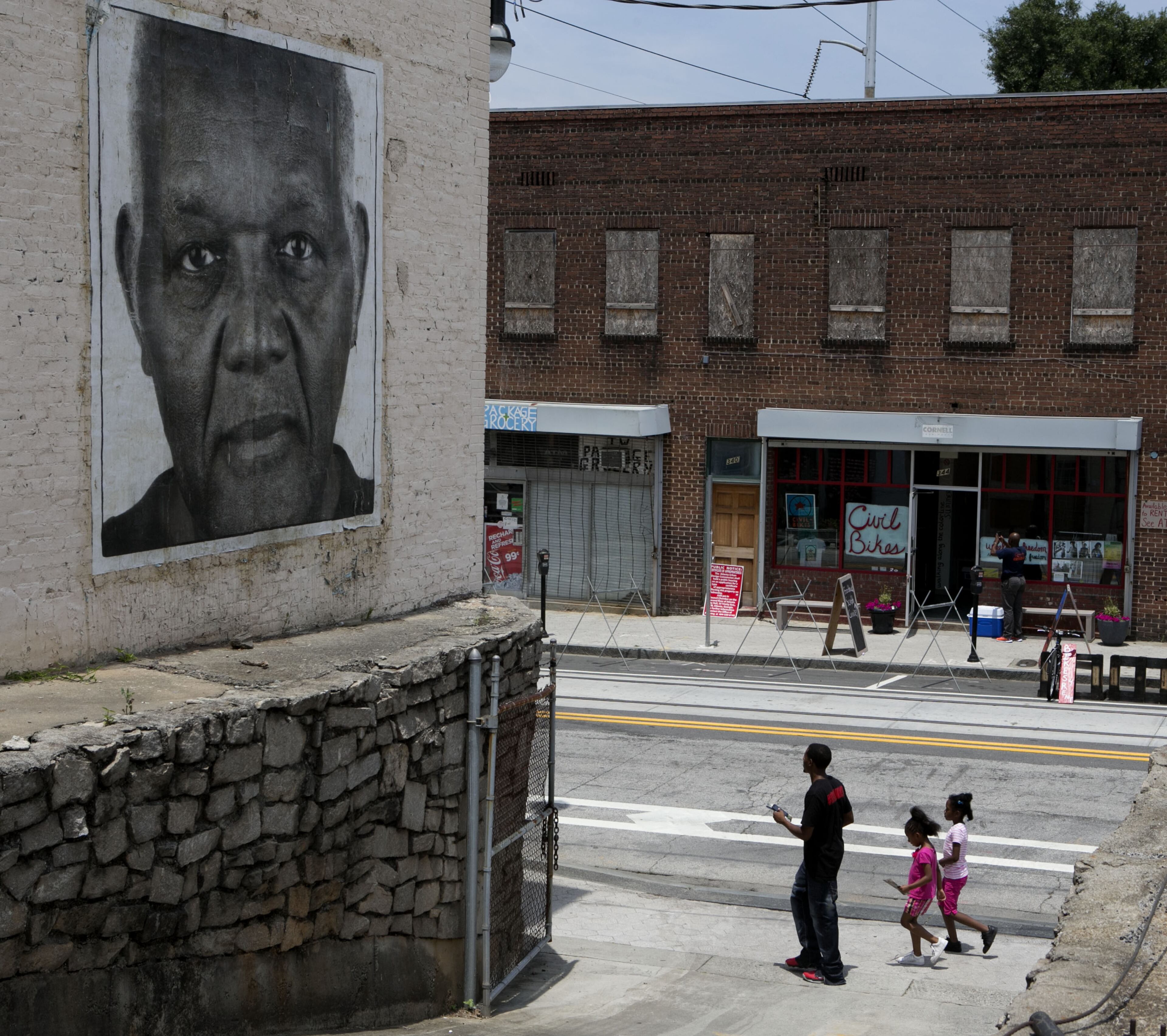 A family walked past a large mural portrait on Auburn Avenue. during the Sweet Auburn Living Beyond Expectations transformation, a multi-year project to demonstrate what it takes to build a community that appeals to older adults & Millennials. (Photo by Phil Skinner)