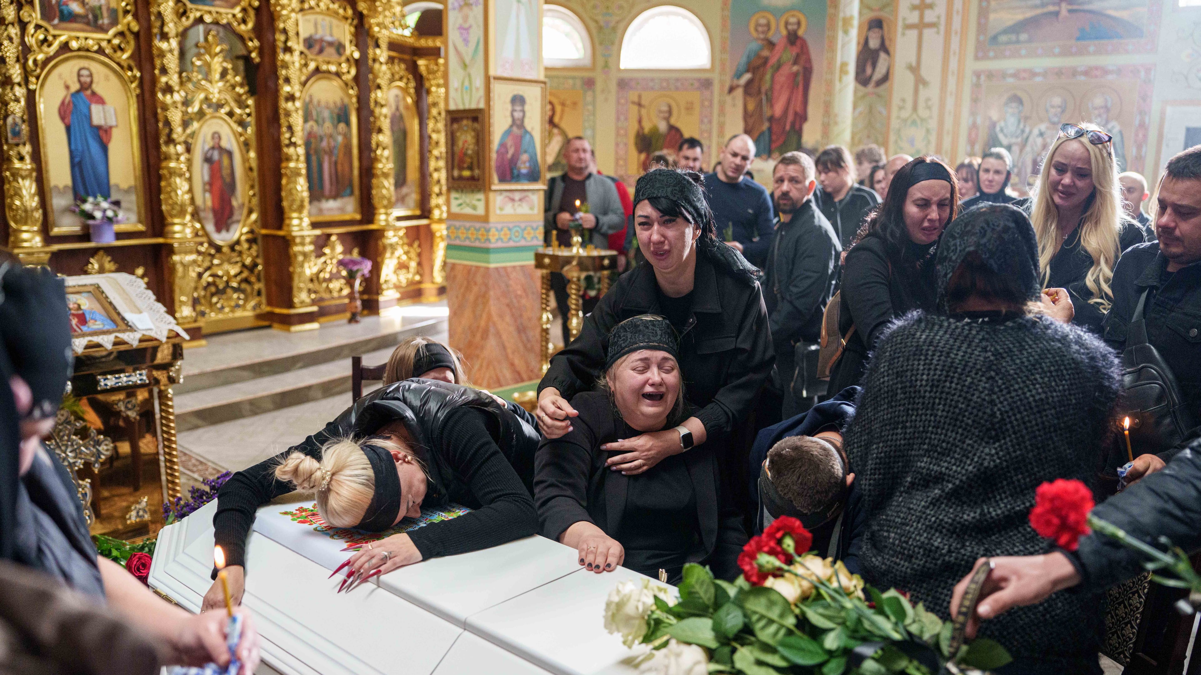 A mother surrounded by family cries sitting by the coffin of her son Illia Honcharenko, 14, killed by a Russian rocket strike on a residential house on Sept. 30, during their funeral, in Vyshhorod, Kyiv region, Ukraine, Friday, Oct. 2, 2026. (AP Photo/Evgeniy Maloletka)