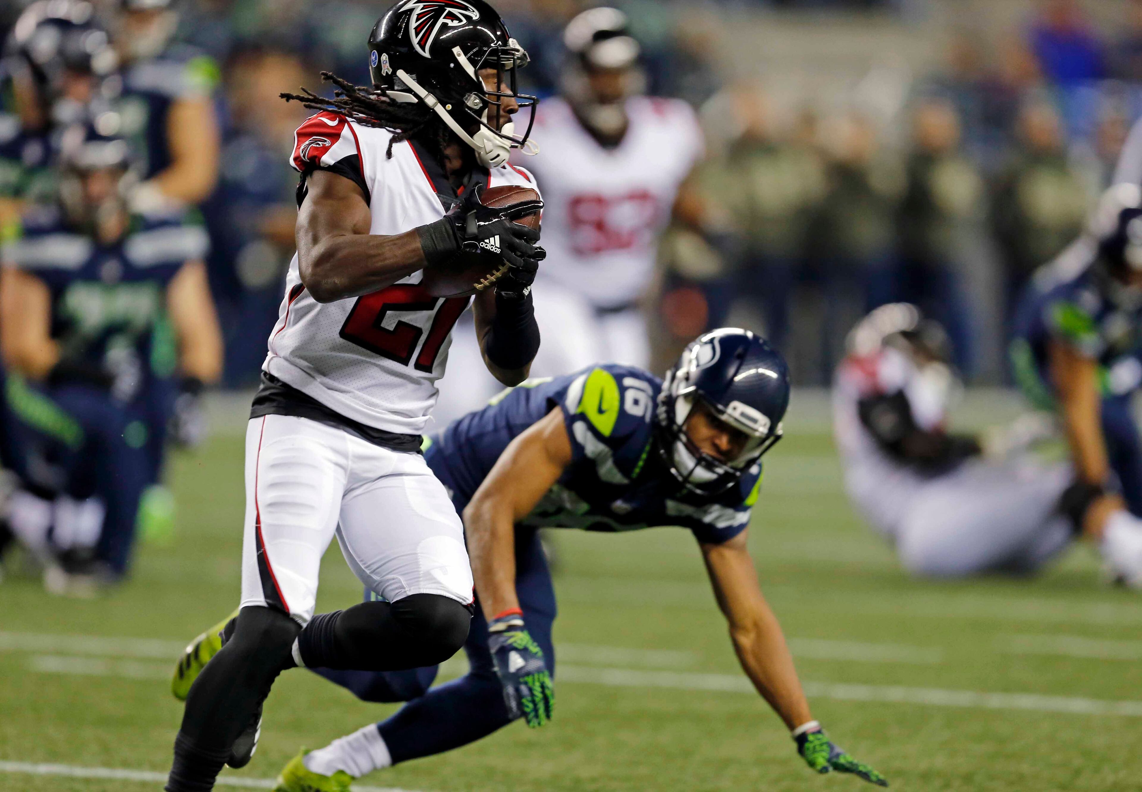 Atlanta Falcons' Desmond Trufant (21) runs with the ball after intercepting it as Seattle Seahawks' Tyler Lockett tumbles behind in the first half of an NFL football game, Monday, Nov. 20, 2017, in Seattle. (AP Photo/Stephen Brashear)