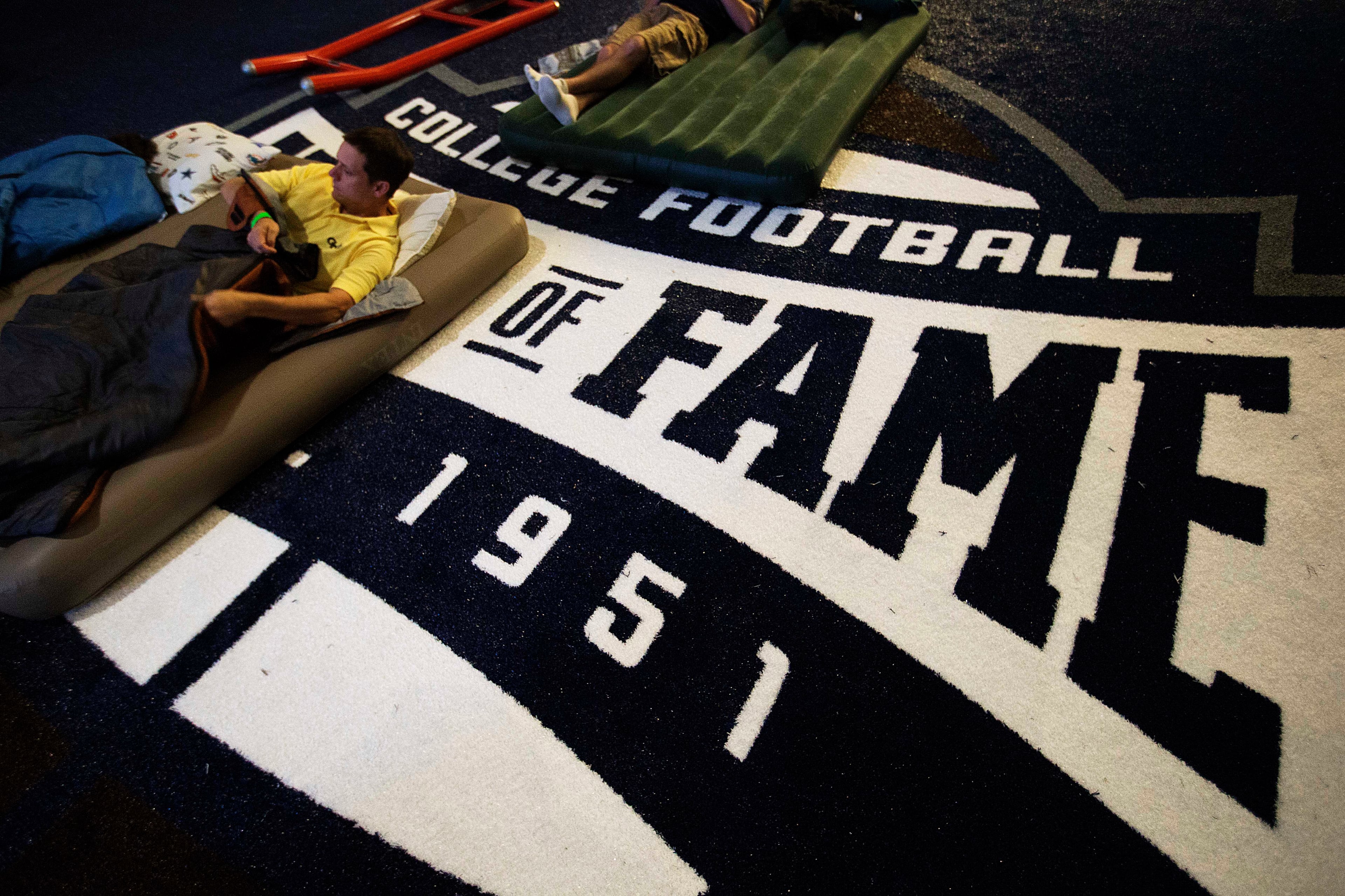 Stephen Edmonds, of Marietta Ga., lies down on an air mattress during a sleepover in the College Football Hall of Fame, Wednesday, Aug. 13, 2014, in Atlanta. Some visitors brought tents, others sleeping bags and air mattresses and a few spent the night sleeping in folding chairs. (AP Photo/David Goldman)