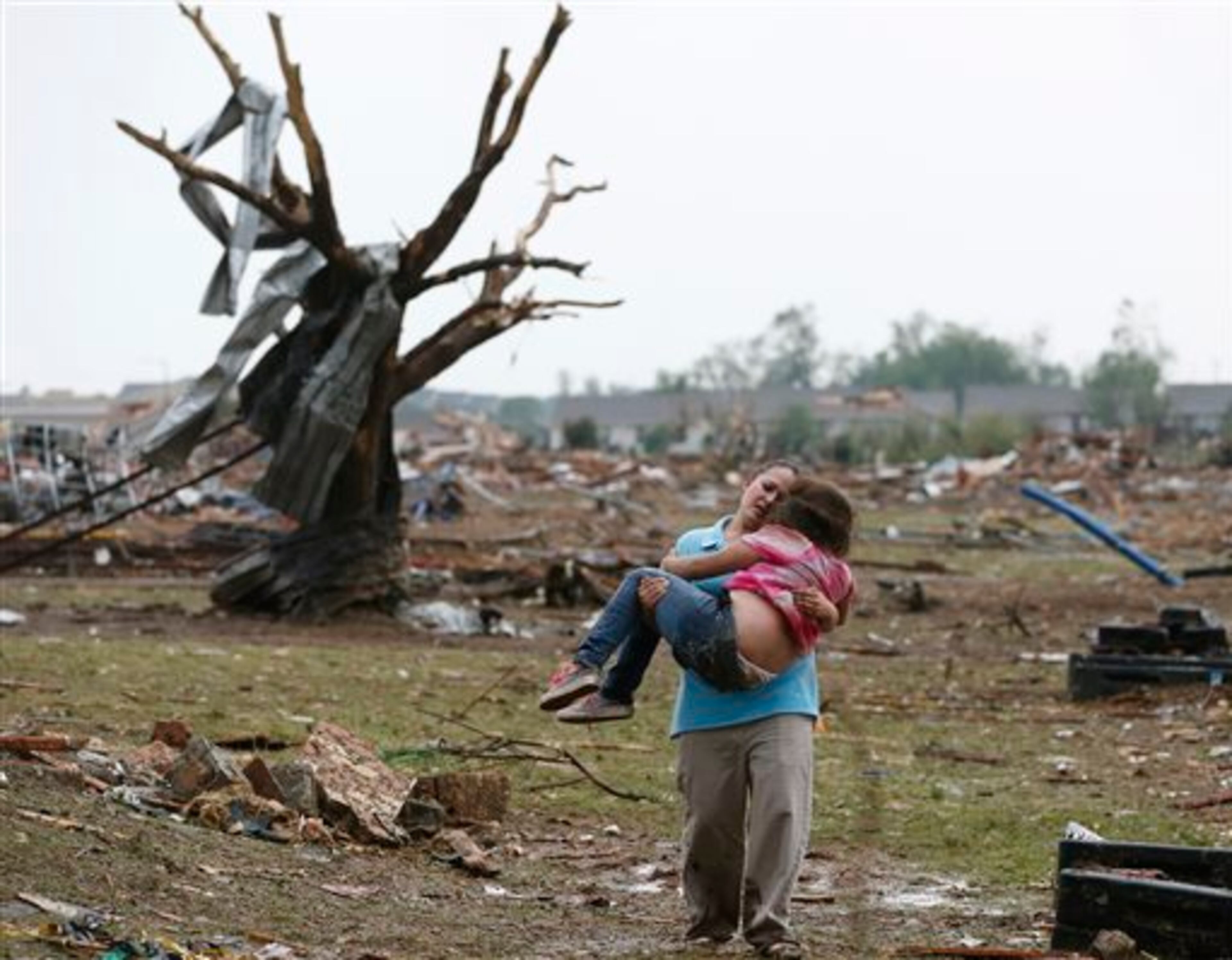 FILE - LaTisha Garcia carries her 8-year-old daughter, Jazmin Rodriguez, near Plaza Towers Elementary School, May 20, 2013, after a massive tornado carved its way through Moore, Okla., leaving little of the school and neighborhood. This image was chosen by the Associated Press as one of the top 10 news photos representing the top stories of 2013. (AP Photo/Sue Ogrocki, File)