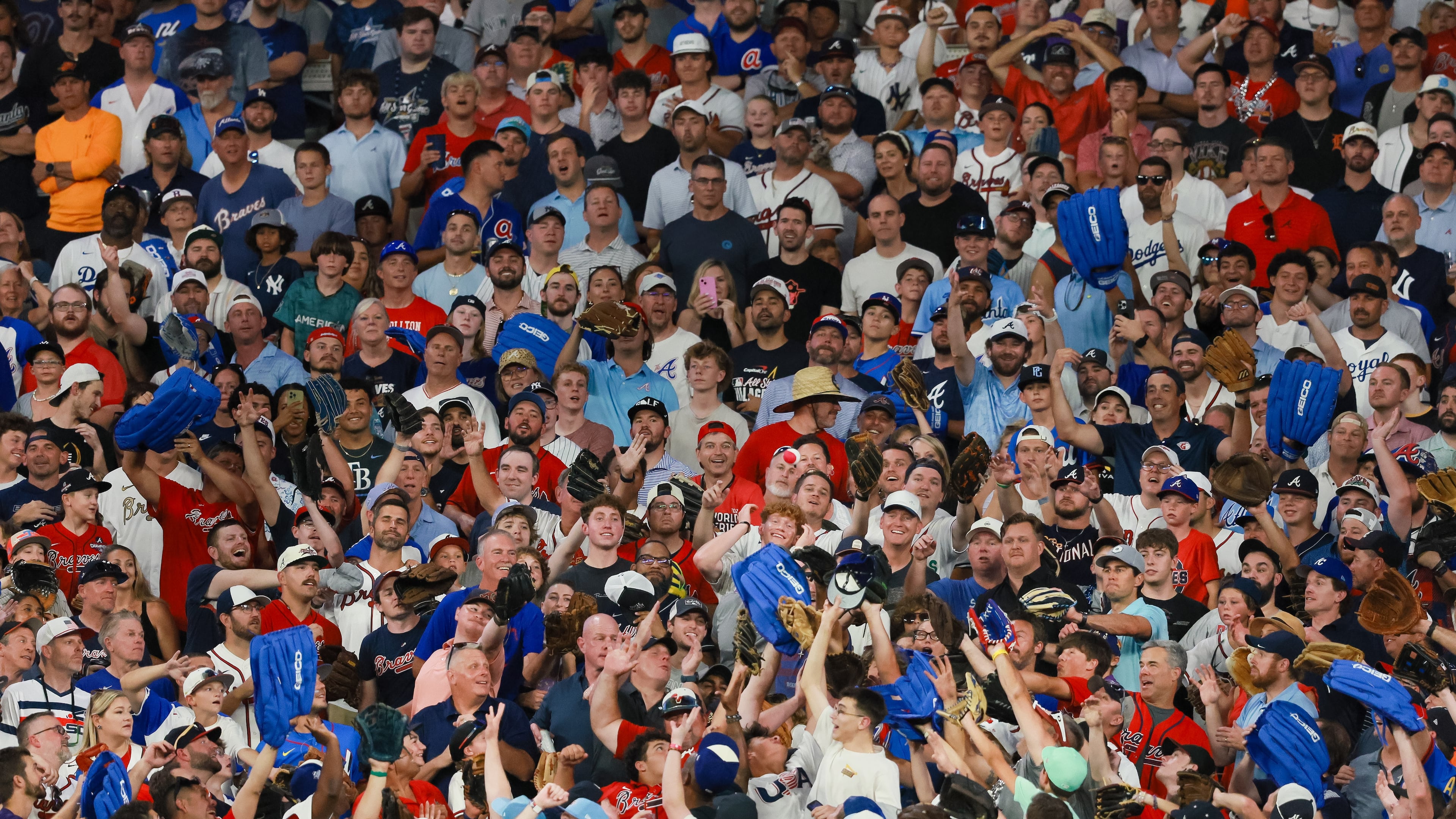 Fans try to catch a home run ball during the MLB Home Run Derby as part of the All-Star Game festivities on Monday, July 14, 2025, at Truist Park in Atlanta. “I wish I was taller,” said a young man in a red polo shirt. (Jason Getz/AJC)
