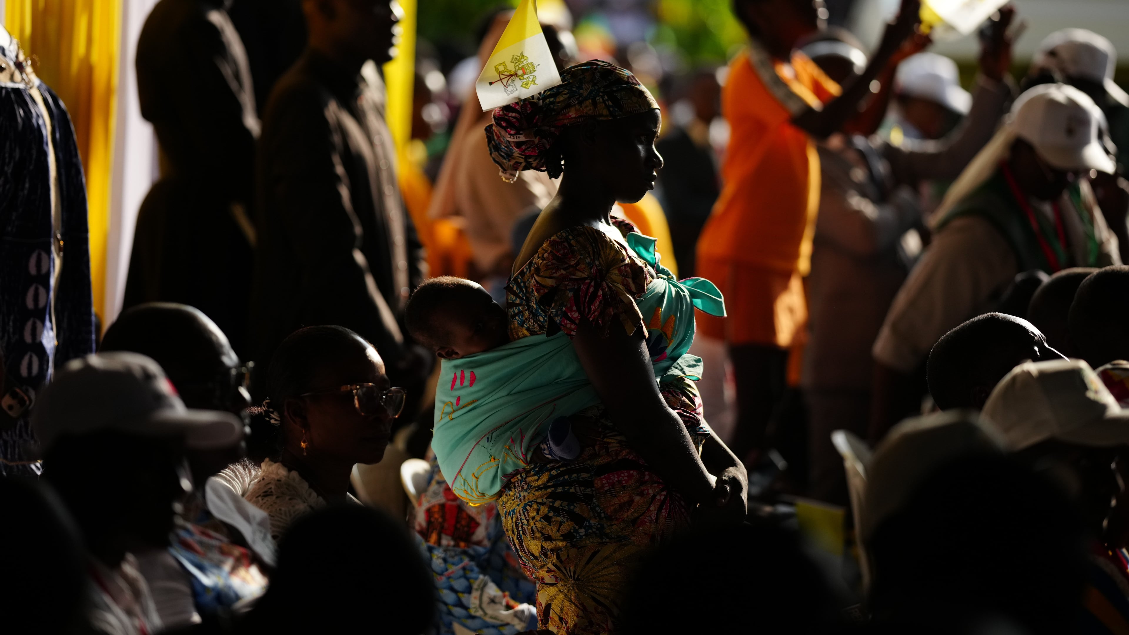 A woman with her child attends Pope Leo XIV's meeting with University students and professors at the Catholic University of Central Africa, in Yaounde Cameroon, Friday, April 17, 2026. (AP Photo/Andrew Medichini)