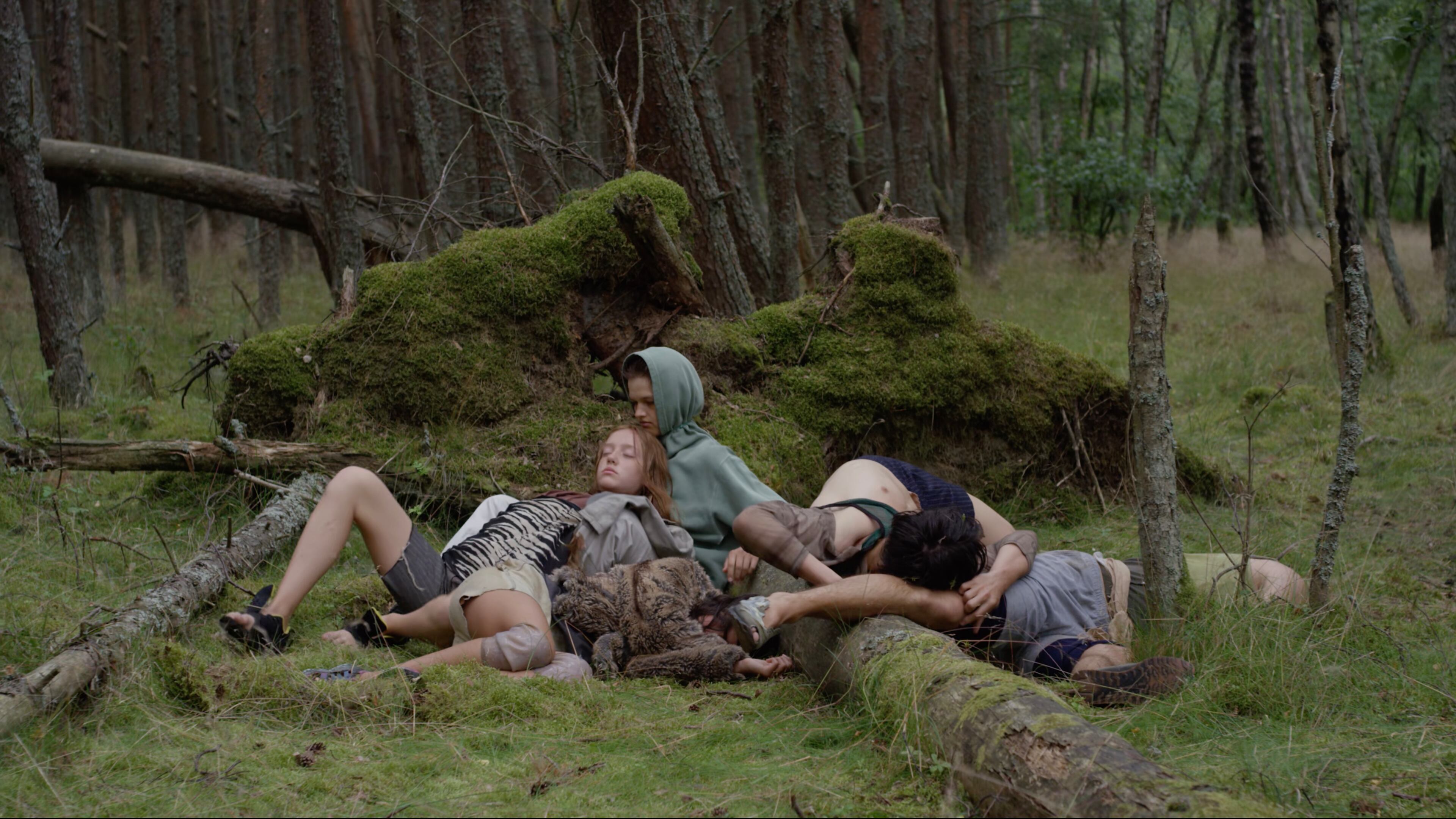 Dancers rest against the mossy surfaces of a dark forest in the dance film "Songs from the Compost," on view at the Michael C. Carlos Museum through May 19.