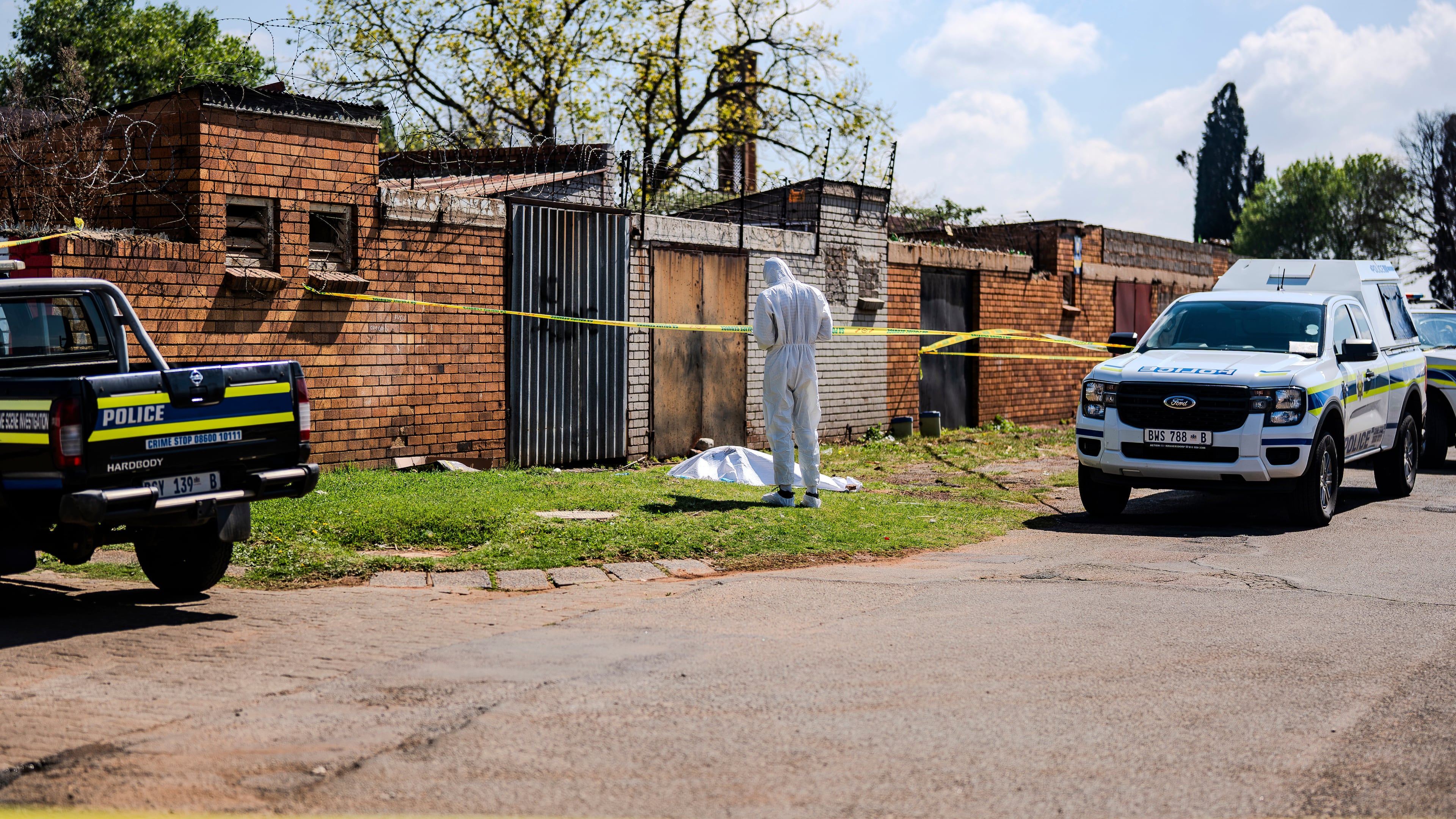 A forensic officer works at the scene where a sixth body, believed to be that of a woman, was found along a road in KwaThema, Springs, South Africa, Tuesday, Sept. 15, 2026. (AP Photo)