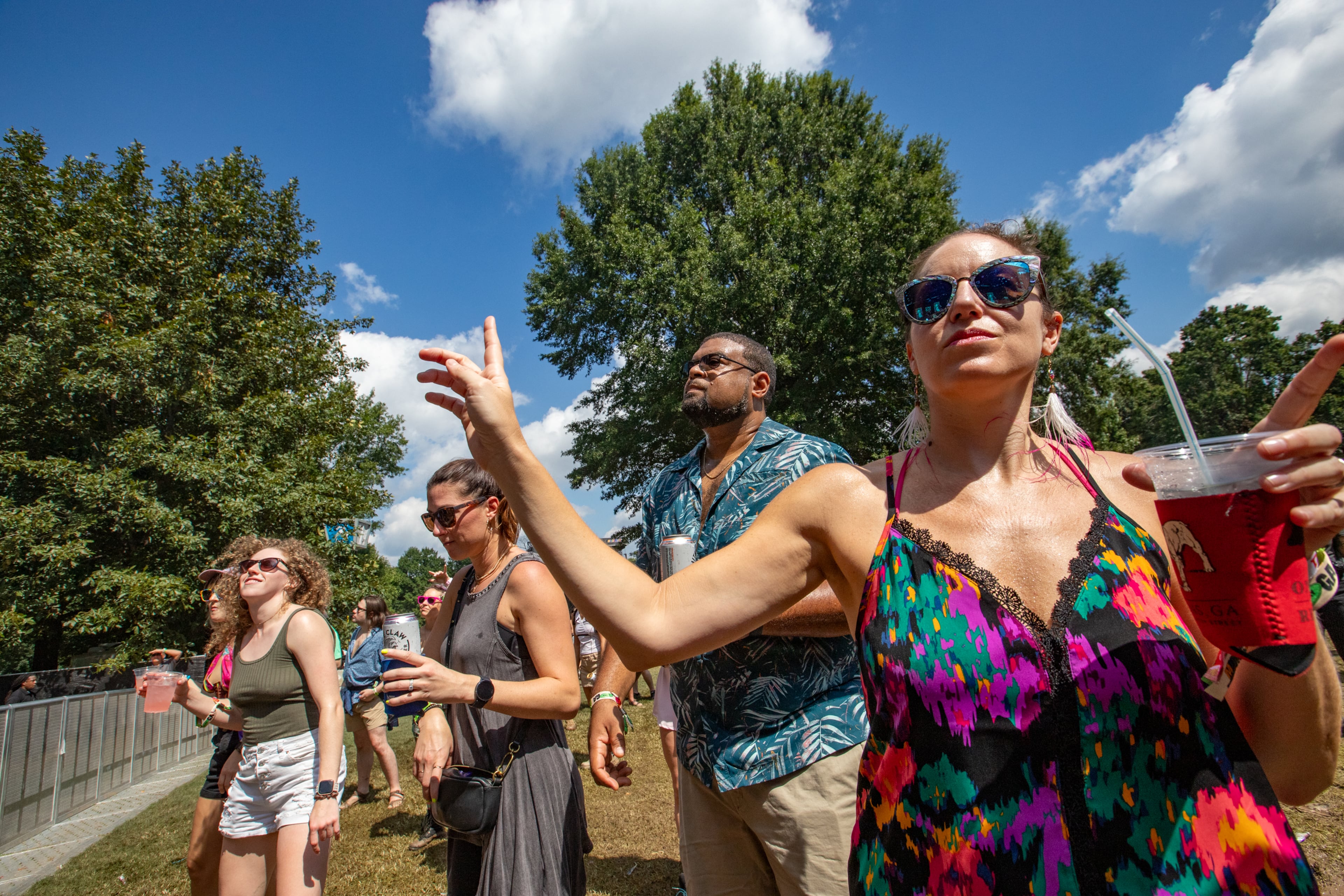 Magic City Hippies are on the Cotton Club stage at Music Midtown where Jenny Carbonell front right, enjoys the show with friends and other fans in Piedmont Park on Sunday, Sept 17, 2023. (Jenni Girtman for The Atlanta Journal-Constitution)