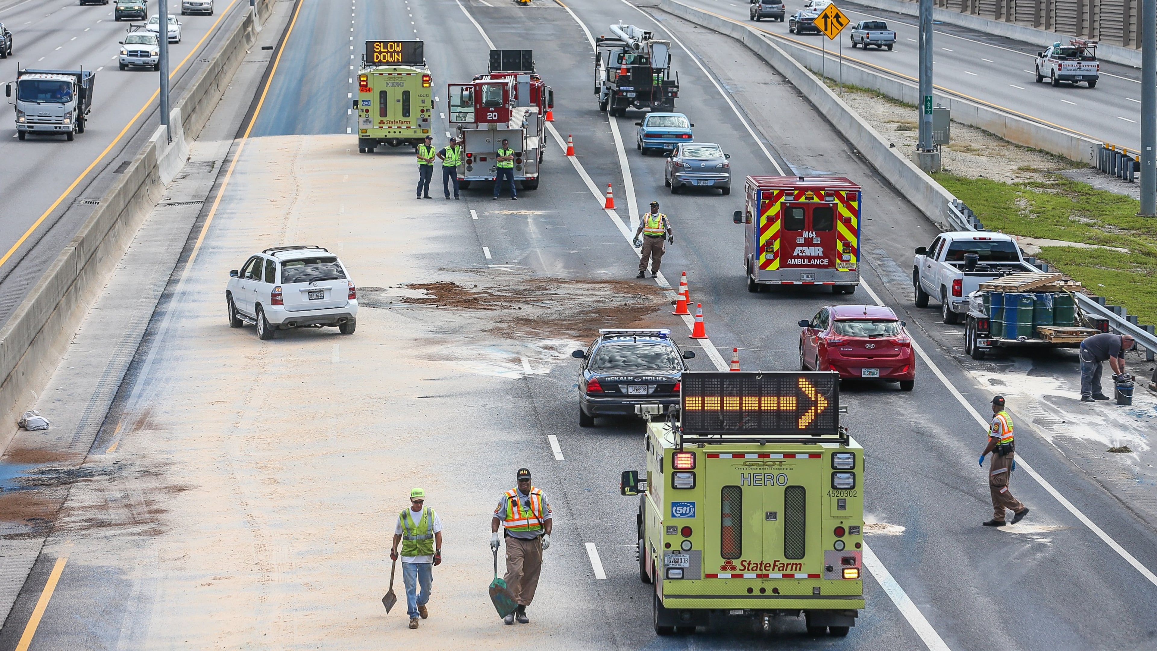 Crews applied sand to the area of large paint spill in DeKalb County on Wed., Sept. 30, 2015. JOHN SPINK / JSPINK@AJC.COM