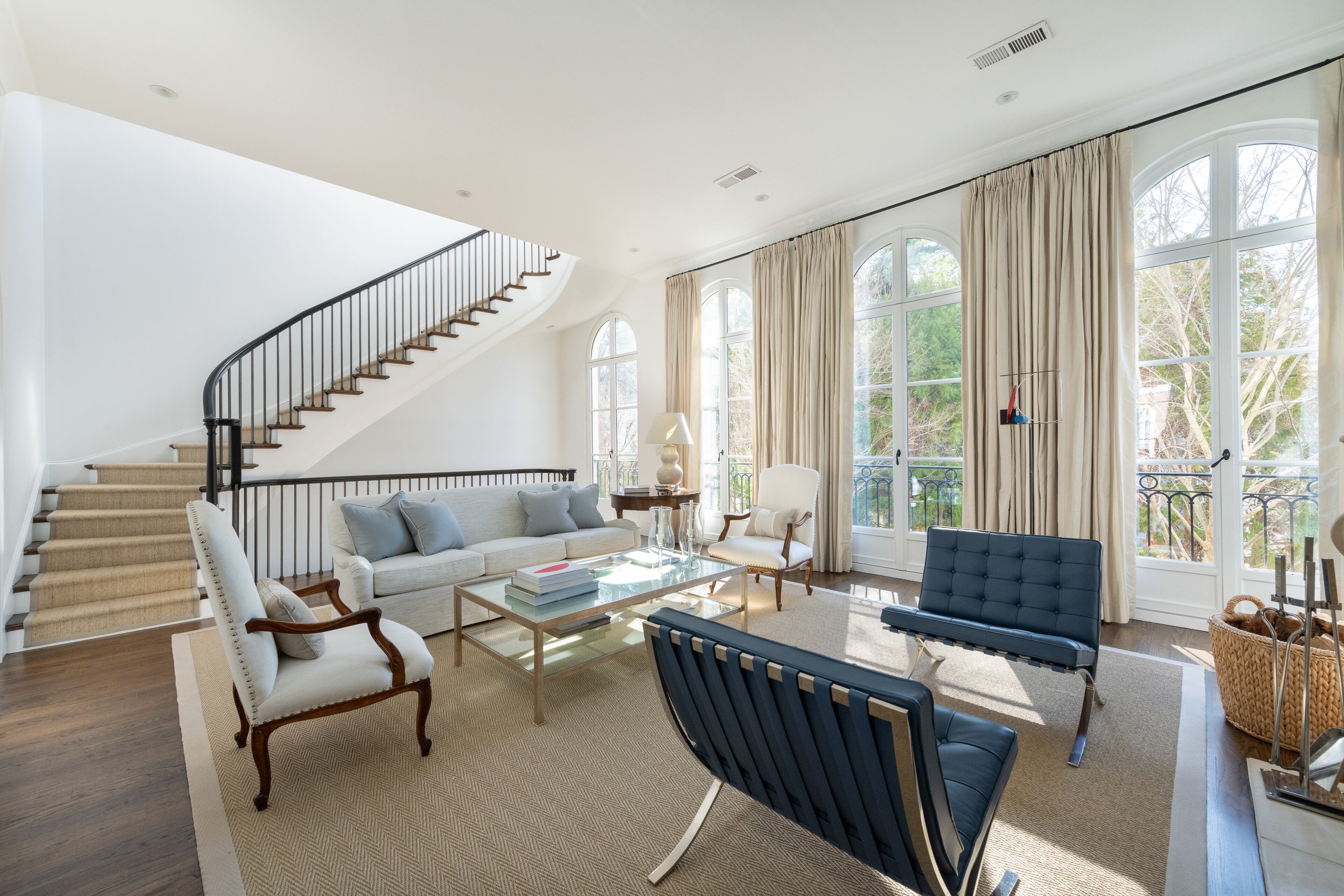 A soaring ceiling and four pairs of transom-topped French doors with Juliet balconies add grandness to this luxurious living room. Text by Ansley Warren