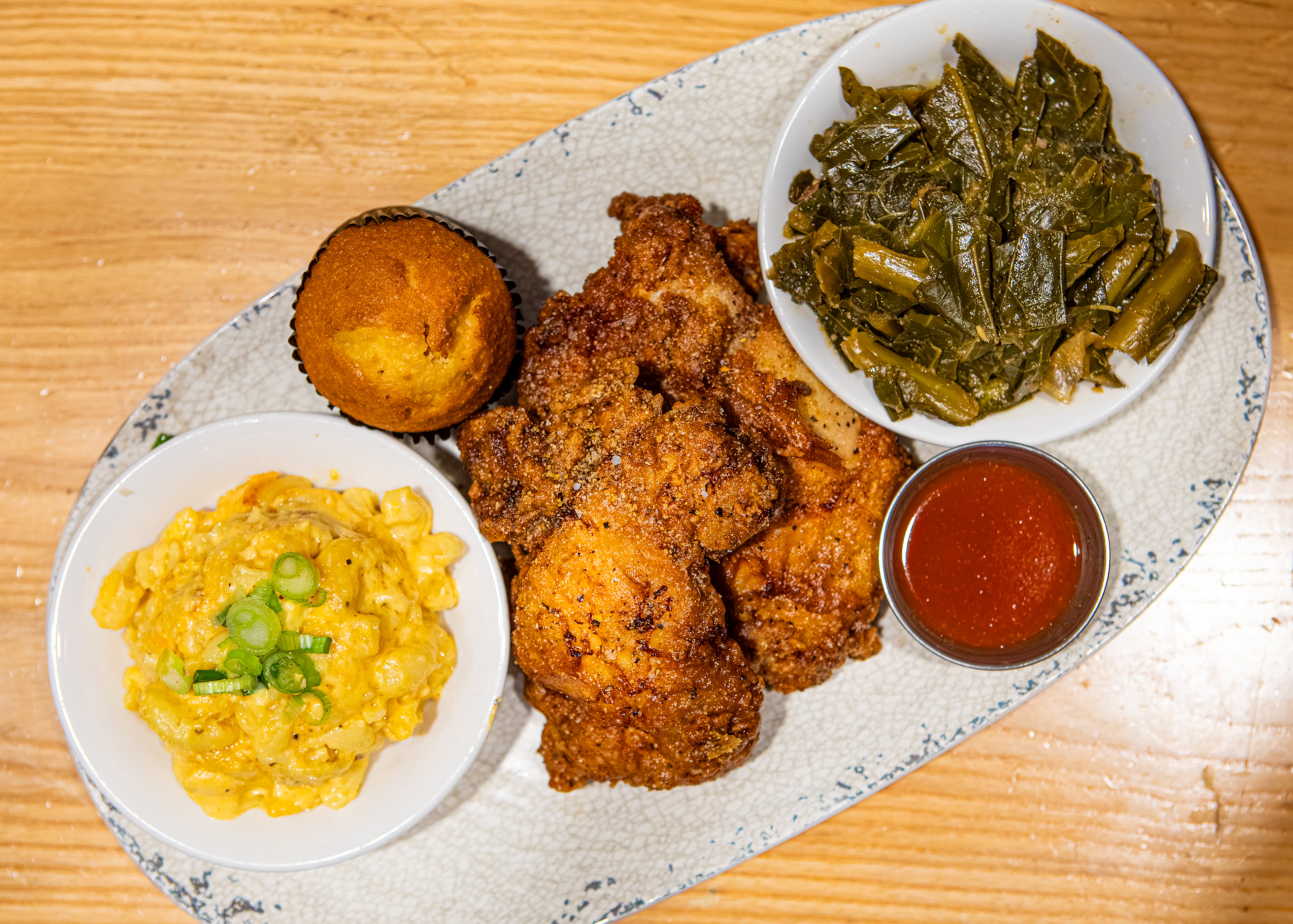 Visit Concourse D for Chicken + Beer's fried chicken plate, shown with macaroni and cheese, a corn bread muffin and collard greens. (Aaliyah Mann for the AJC)