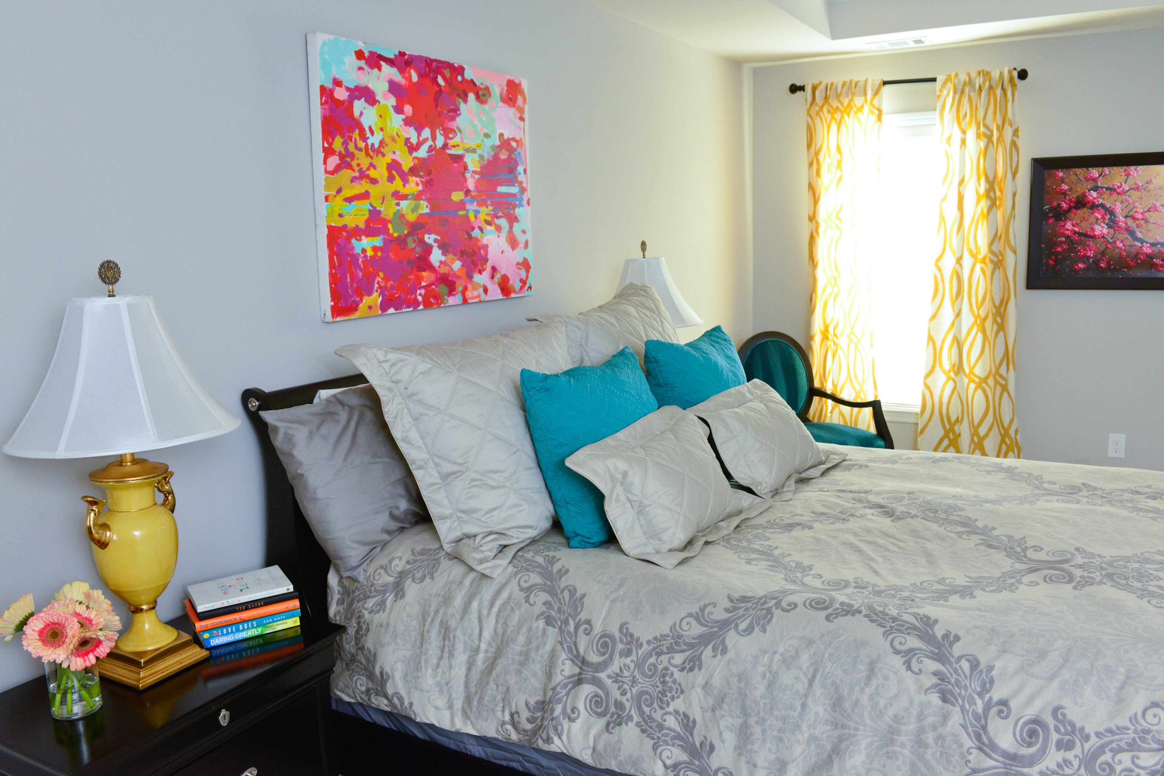 An abstract painting by artist Michelle Armas from Gregg Irby Fine Art hangs above the bed from American Signature. The bedside chair was recovered in a green velvet from Lewis & Sheron Textiles. Text by Lori Johnston and Keith Still/Fast Copy News Service.