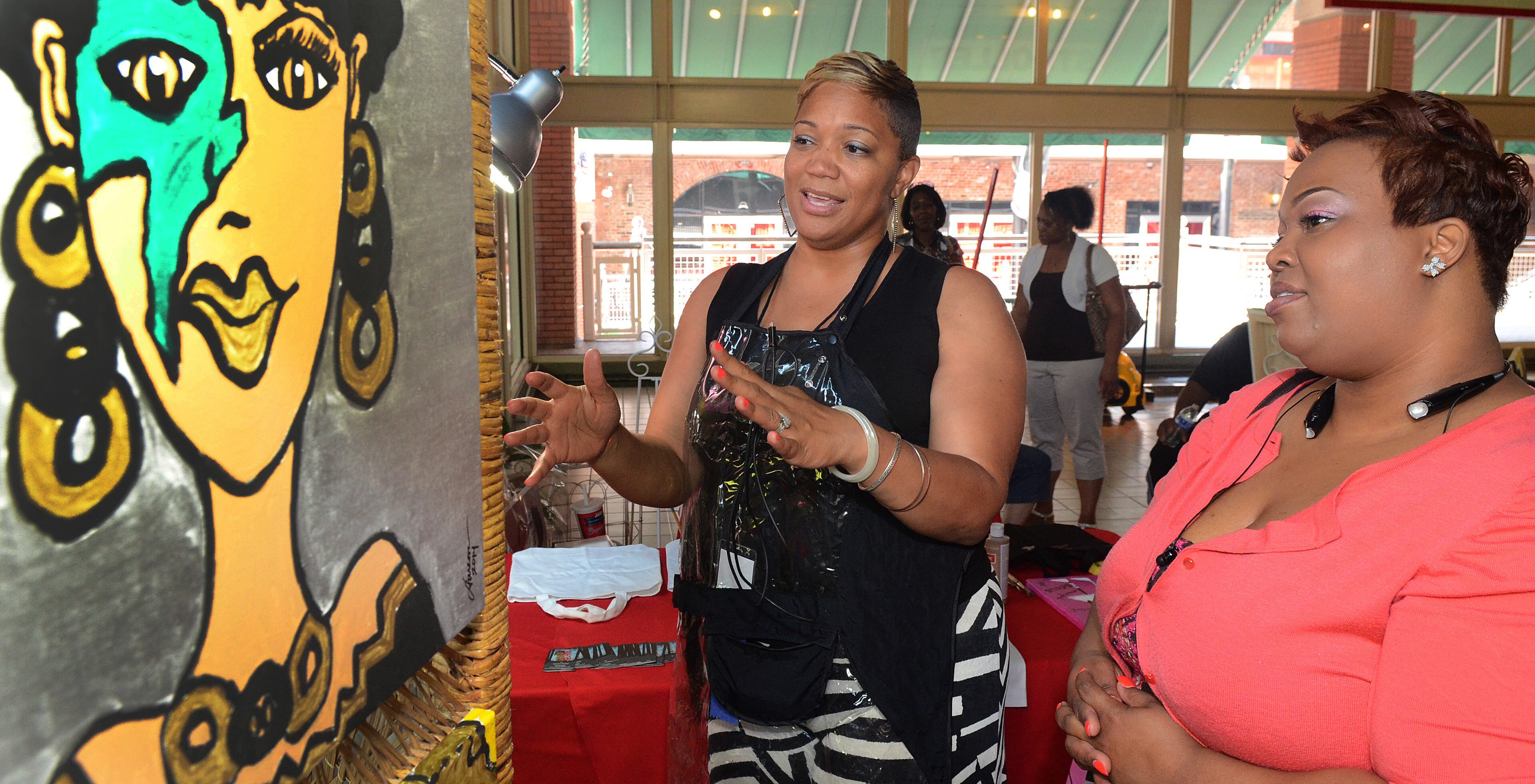 Artist Darcova Triplett explains the techniques and inspiration behind one of her pieces to prospective buyer Niquar Baldwin-Hackett, in the Emerging Artist market area of the 19th Annual Heritage Arts and Soul Festival at Underground Atlanta. The event features the work of over 30 artist, featuring fine art and wearable art ,plus an emerging artist pavillion, fashion show. (CHRIS HUNT/SPECIAL)