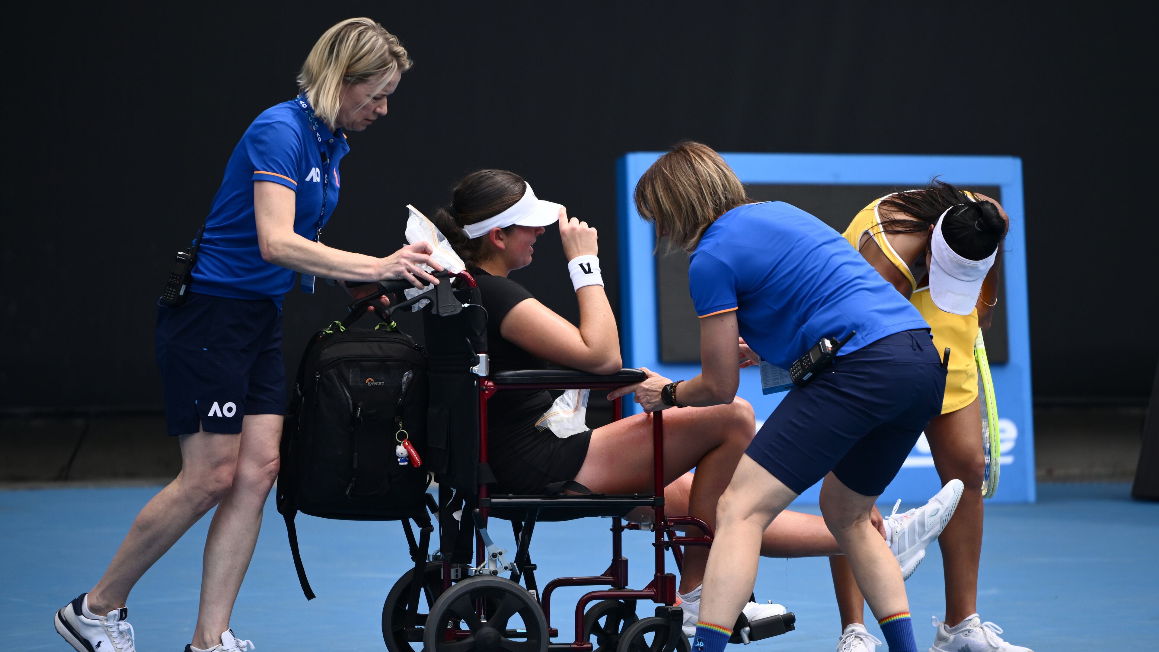 Marina Stakusic of Canada is taken from the court in a wheelchair after retiring in her first round match against Priscilla Hon, right, of Australia at the Australian Open tennis tournament in Melbourne, Australia, Monday, Jan. 19, 2026. (Joel Carrett/AAP Image via AP)