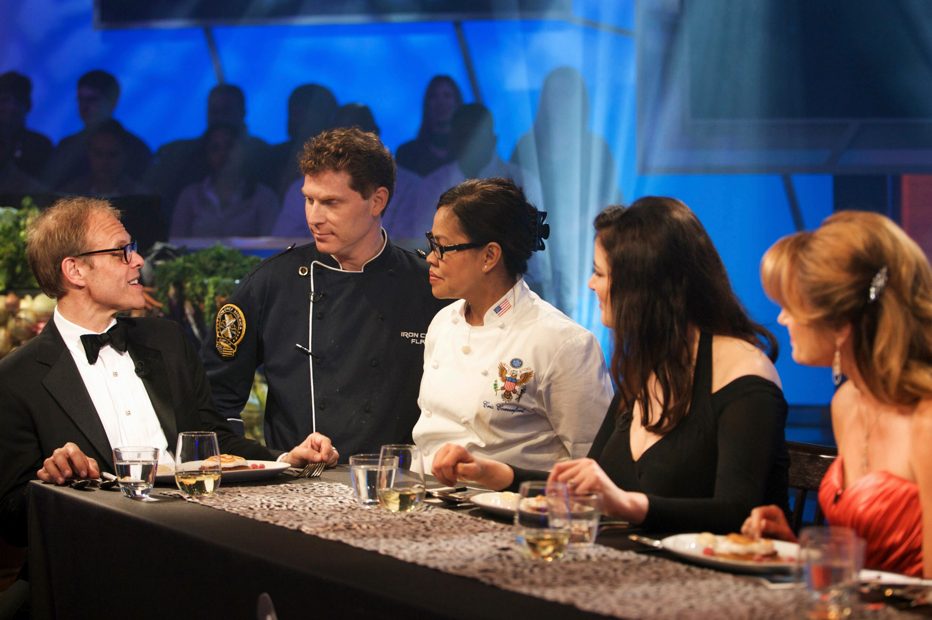 This Food Network photo shows Alton Brown, from left, talking with chef team Bobby Flay and Cristeta Comerford at the judging table in the Kitchen Stadium at the Food Network studio in New York.
