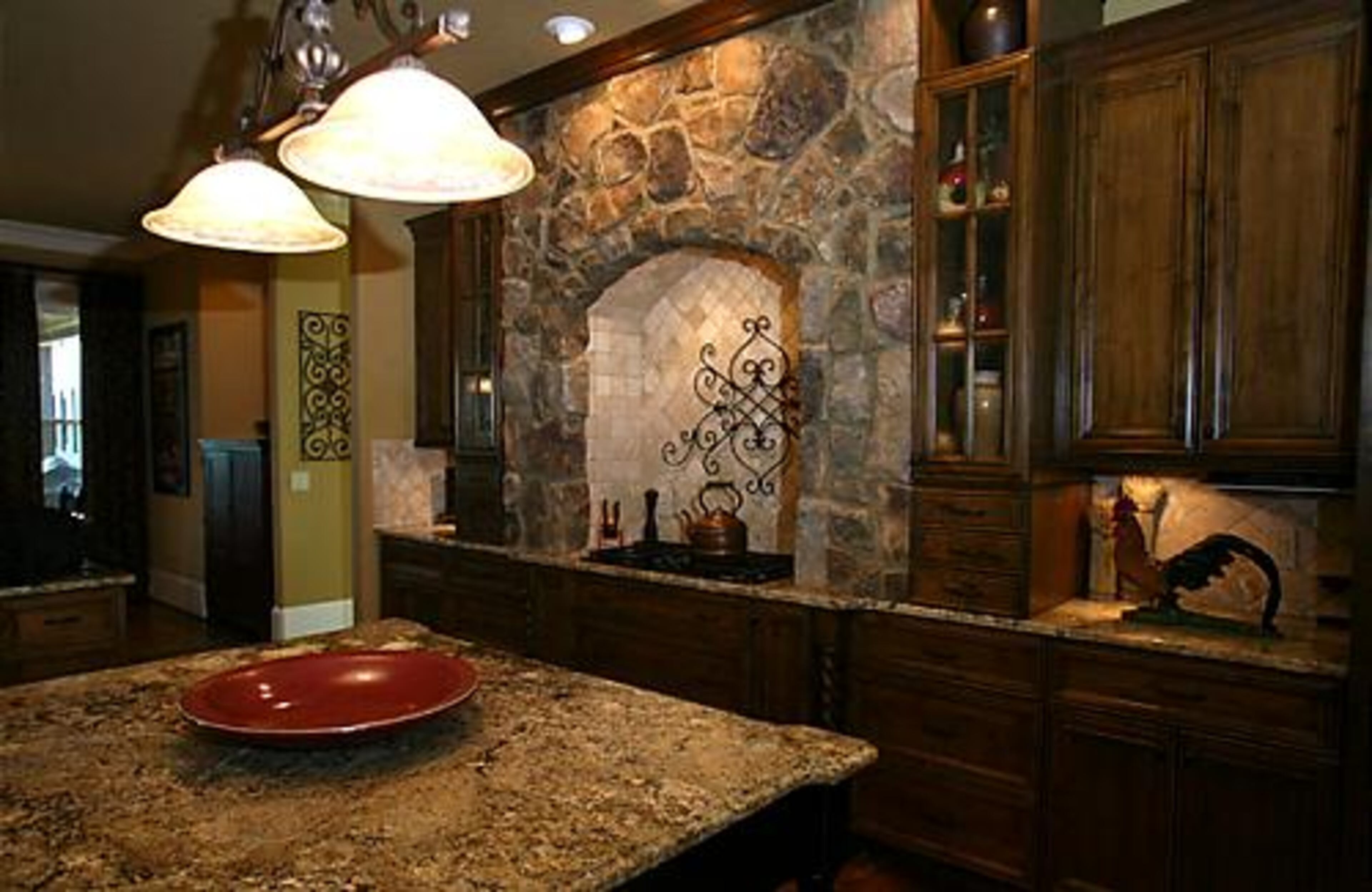 A stone archway surrounds the cooktop in the kitchen. Pam chose cream-colored granite counters and a chestnut antique stain for the cabinets.