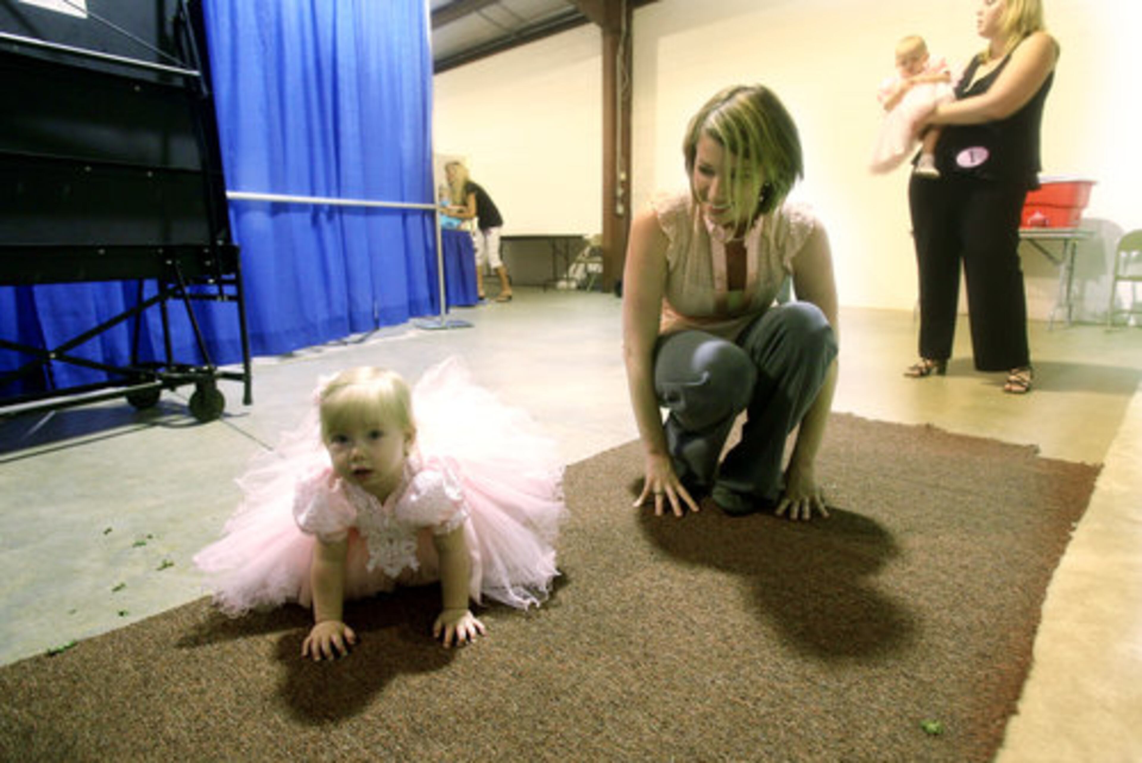 Renee Britt lets her 13-month-old daughter, Shae Lene Britt, crawl around before taking the stage for the Gwinnett County Fair pageant. The Britts live in Hoschton.