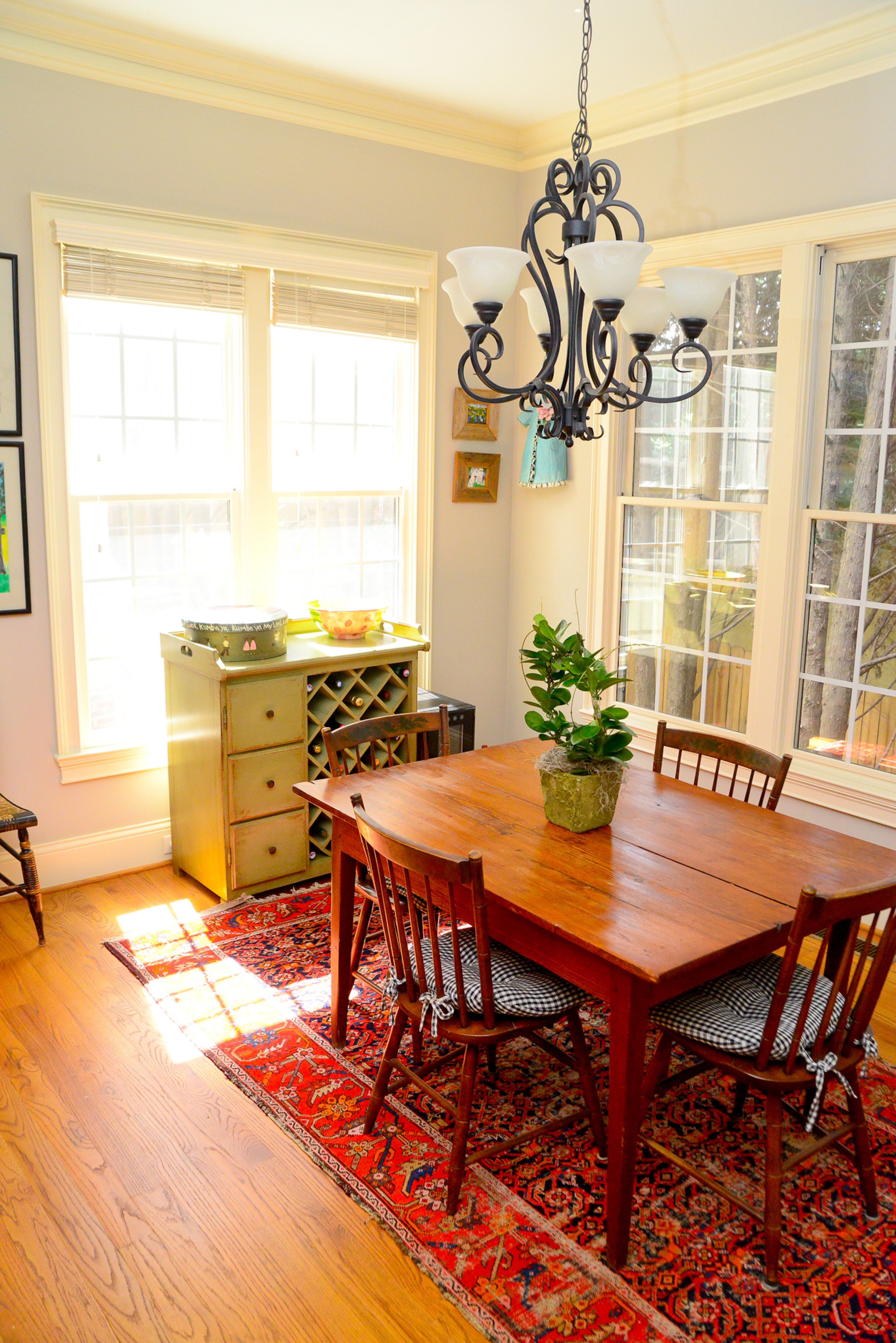 A sunny eat-in kitchen is a cozy spot for meals, with a wood table and chairs that fit with the early American-style interiors.