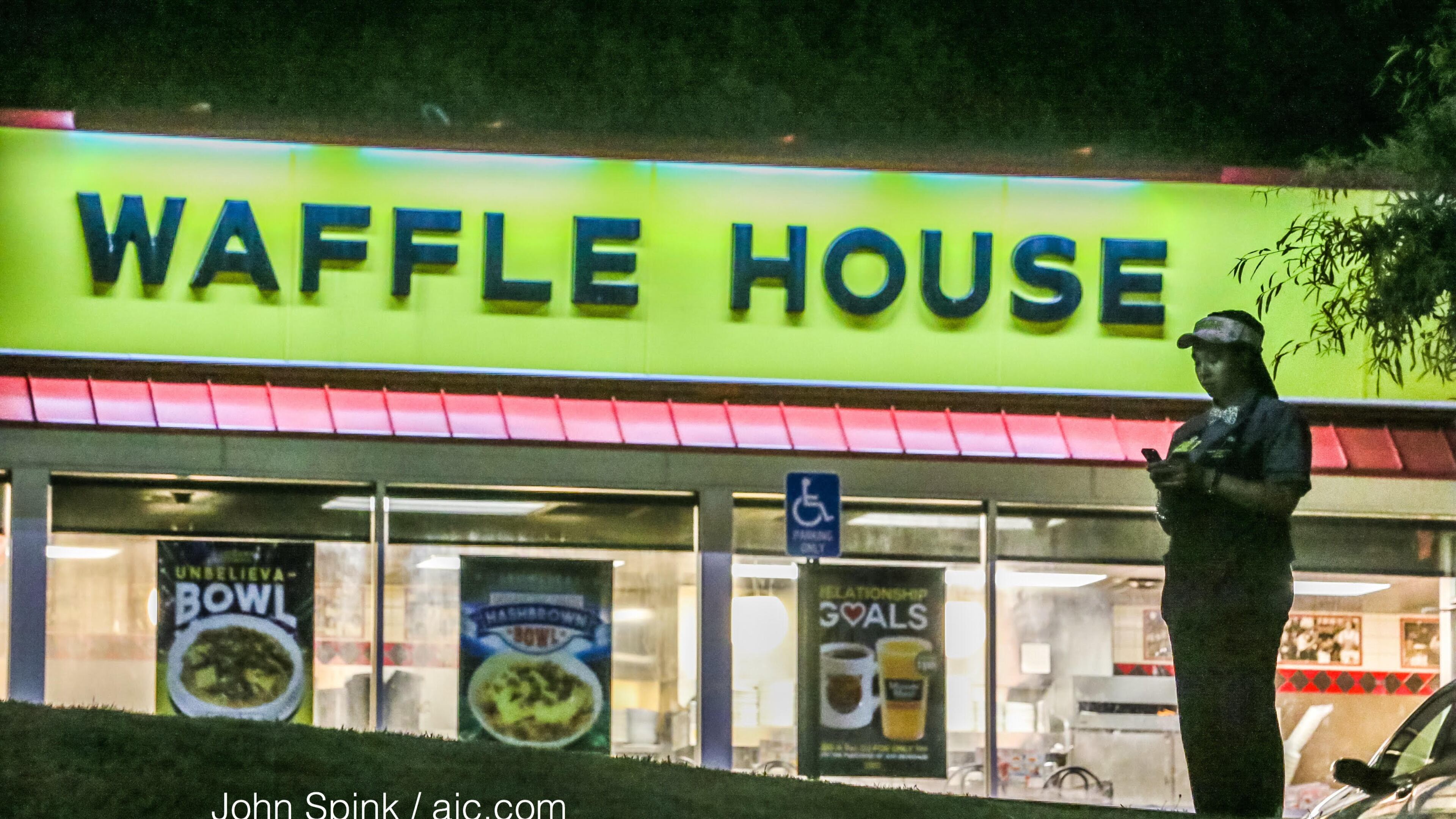 A Waffle House employee stands in the parking lot where a woman was fatally shot on Flat Shoals Parkway in DeKalb County. JOHN SPINK / JSPINK@AJC.COM