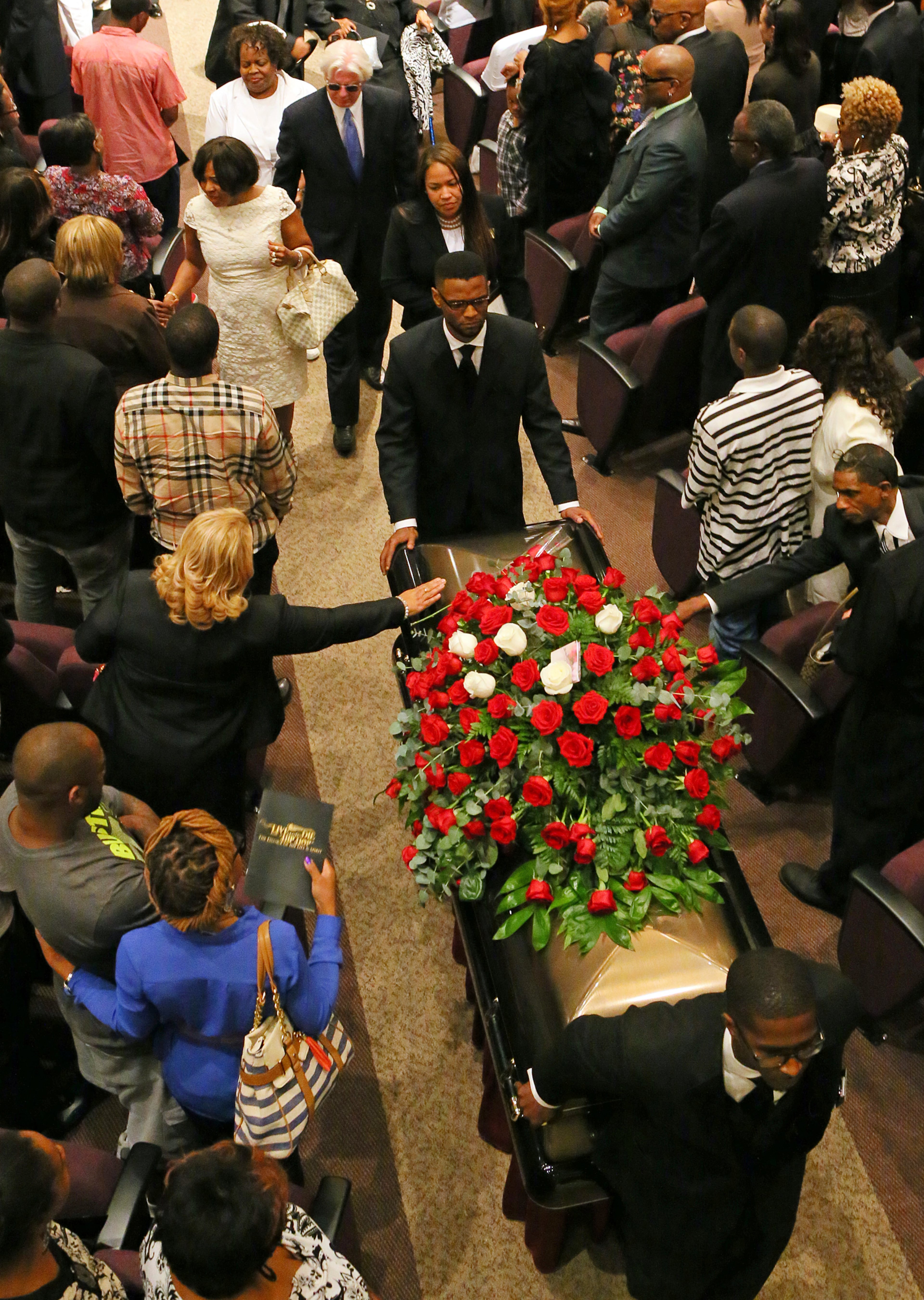 A mourner reaches out to touch the coffin of Chris Kelly.