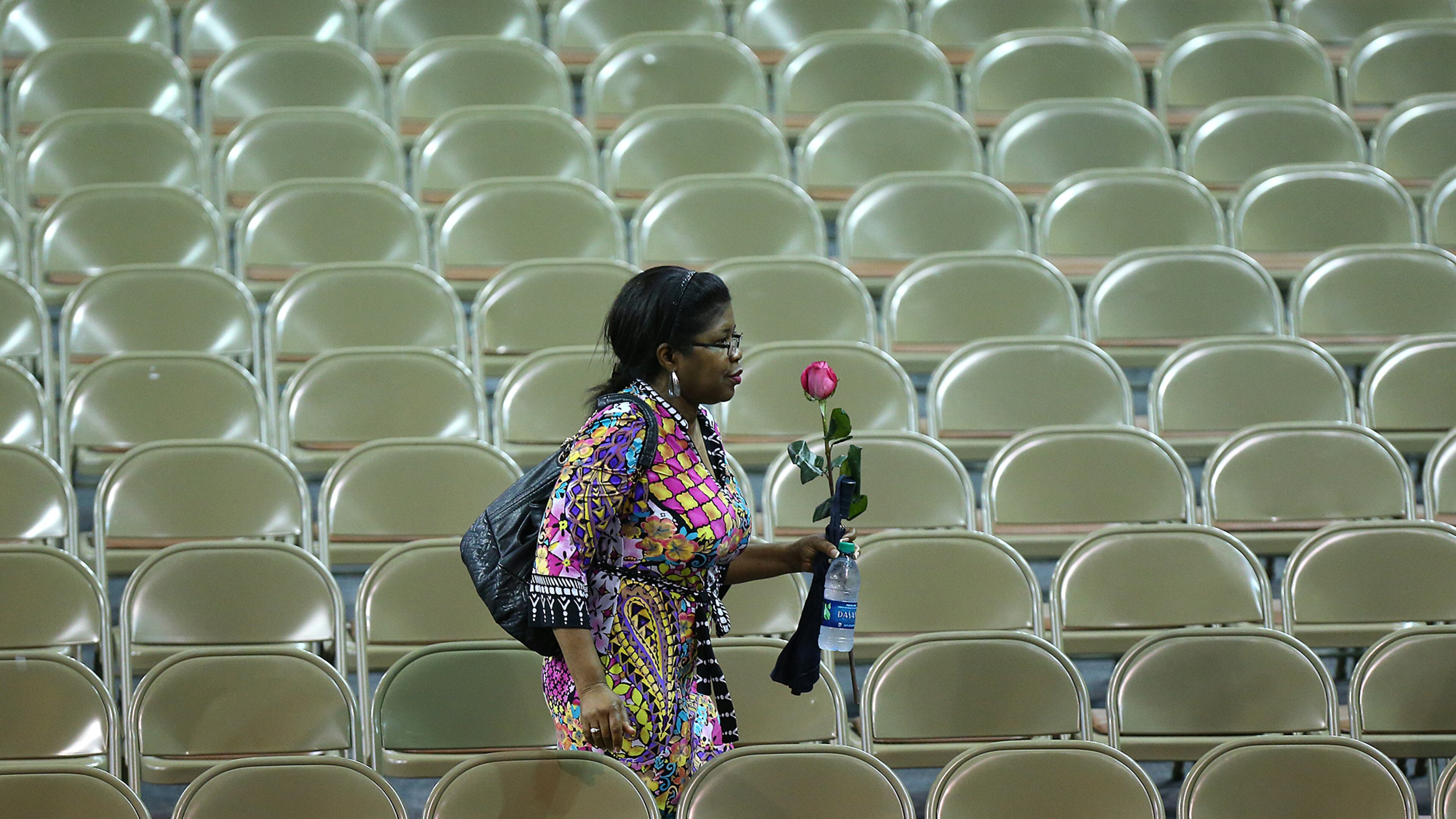 A woman carries a single rose as she enters TD Arena for a public memorial service at the College of Charleston for the victims of the Emanuel AME Church shooting on Friday. Curtis Compton, ccompton@ajc.com