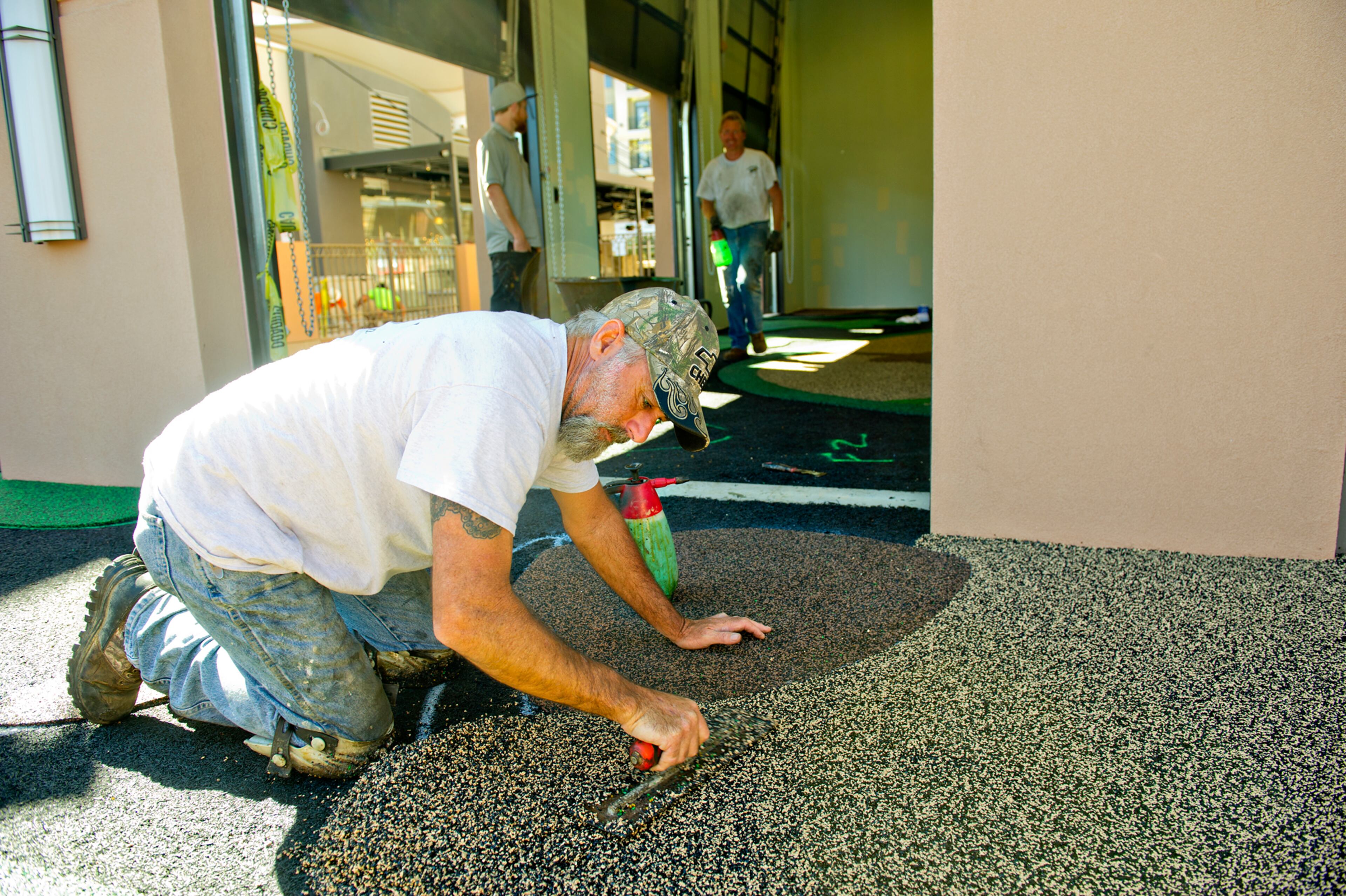 Glenn Gauthier spreads safety rubber surfacing inside one of the family zones.