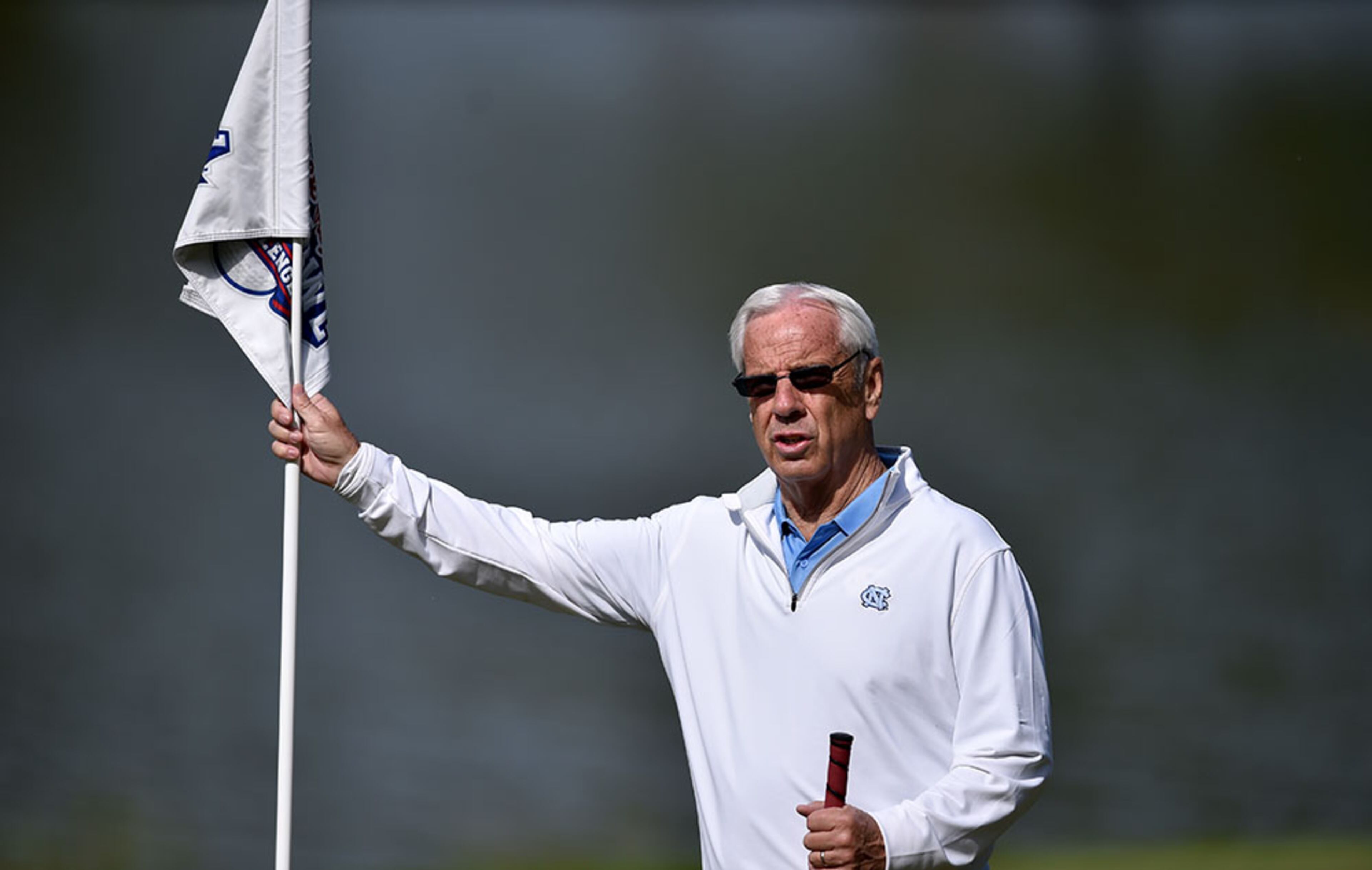 North Carolina head basketball coach Roy Williams tends the flag for UNC head football coach Larry Fedora during the Chick-fil-A Peach Bowl Challenge on Tuesday, April 28, 2015, at Reynolds Plantation at Lake Oconee.