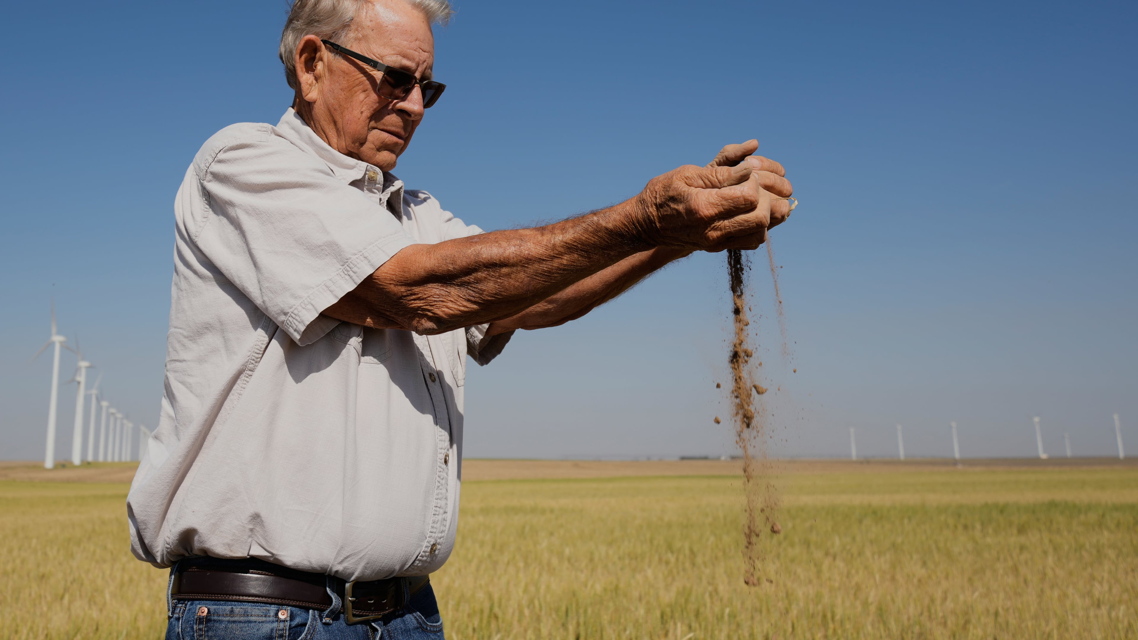 Farmer Orville Williams sifts powder dry soil as he checks the moisture in a drought-stressed wheat field Saturday, May 16, 2026, on his farm near Montezuma, Kan. (AP Photo/Charlie Riedel)