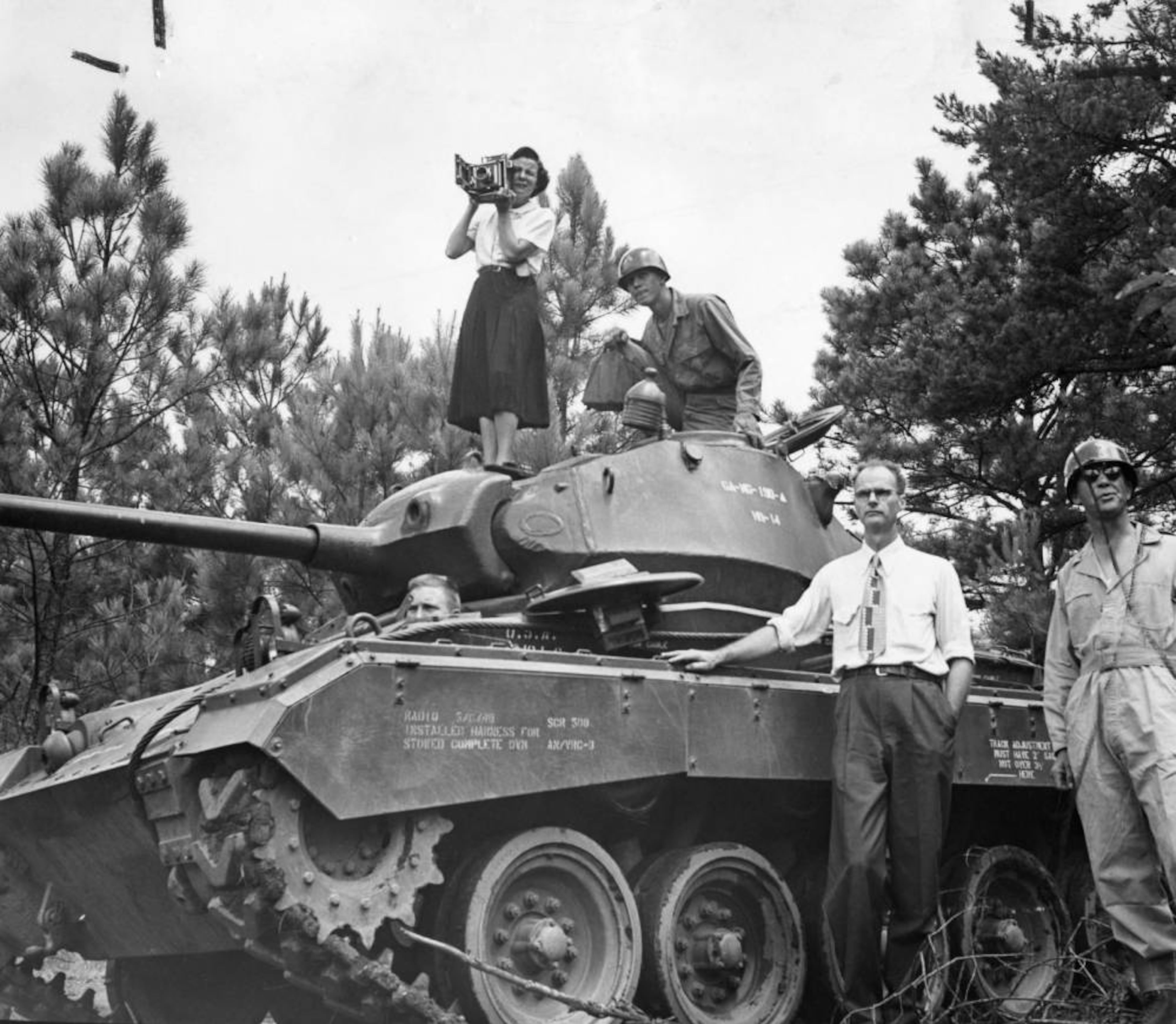 Photojournalist Carolyn Carter of the Atlanta Journal on a tank, 1950. She was working on a story with reporter Willard Neal, the non-uniformed man standing beside the tank. AJC file