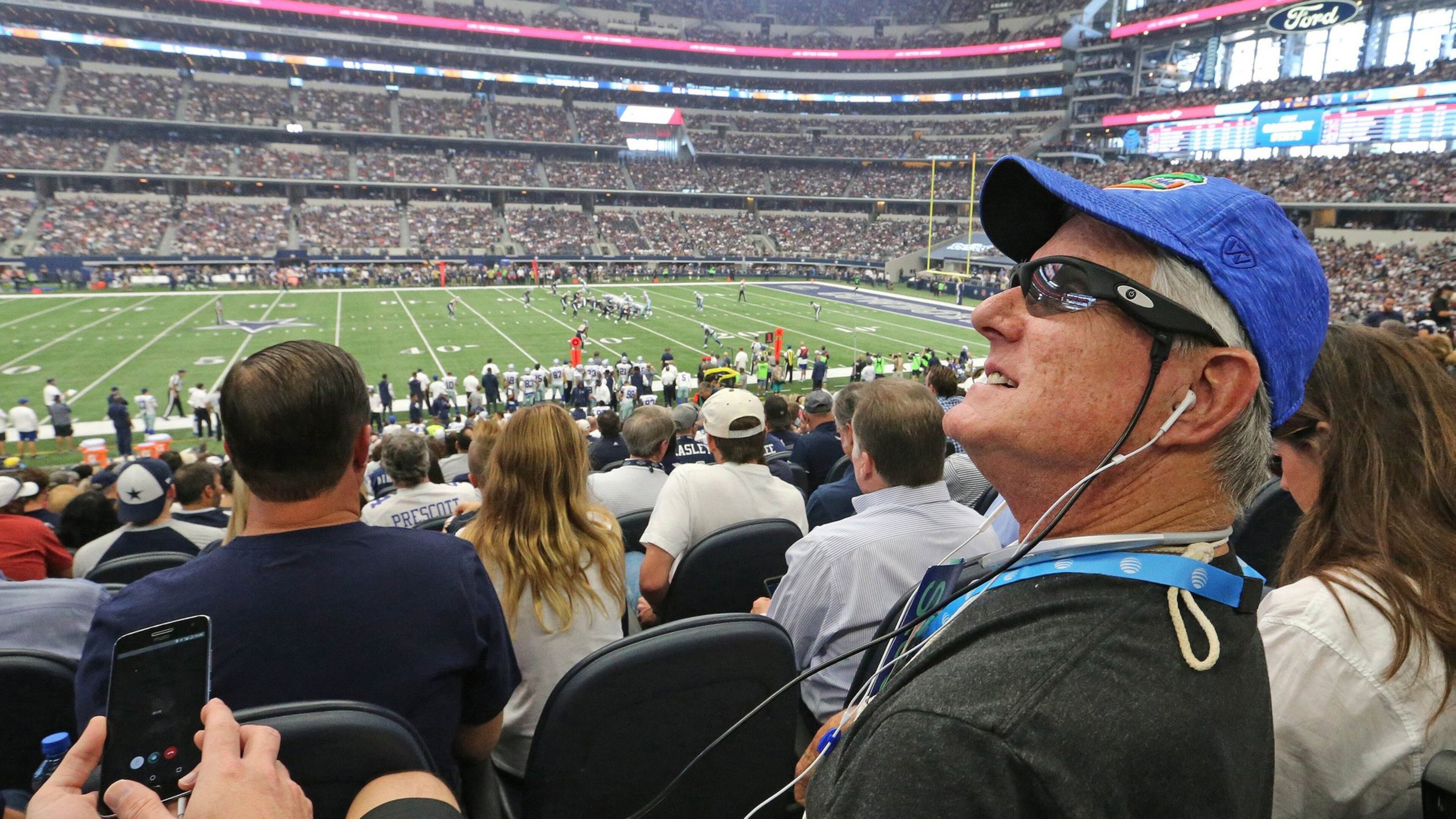 Pete Lane, who is visually impaired, sits in the stands as Dallas Cowboys Hall of Famer Emmitt Smith uses Aira technology for the blind and visually impaired to provide game day play-by-play announcing from the suite level for him. (Louis DeLuca/Dallas Morning News/TNS)