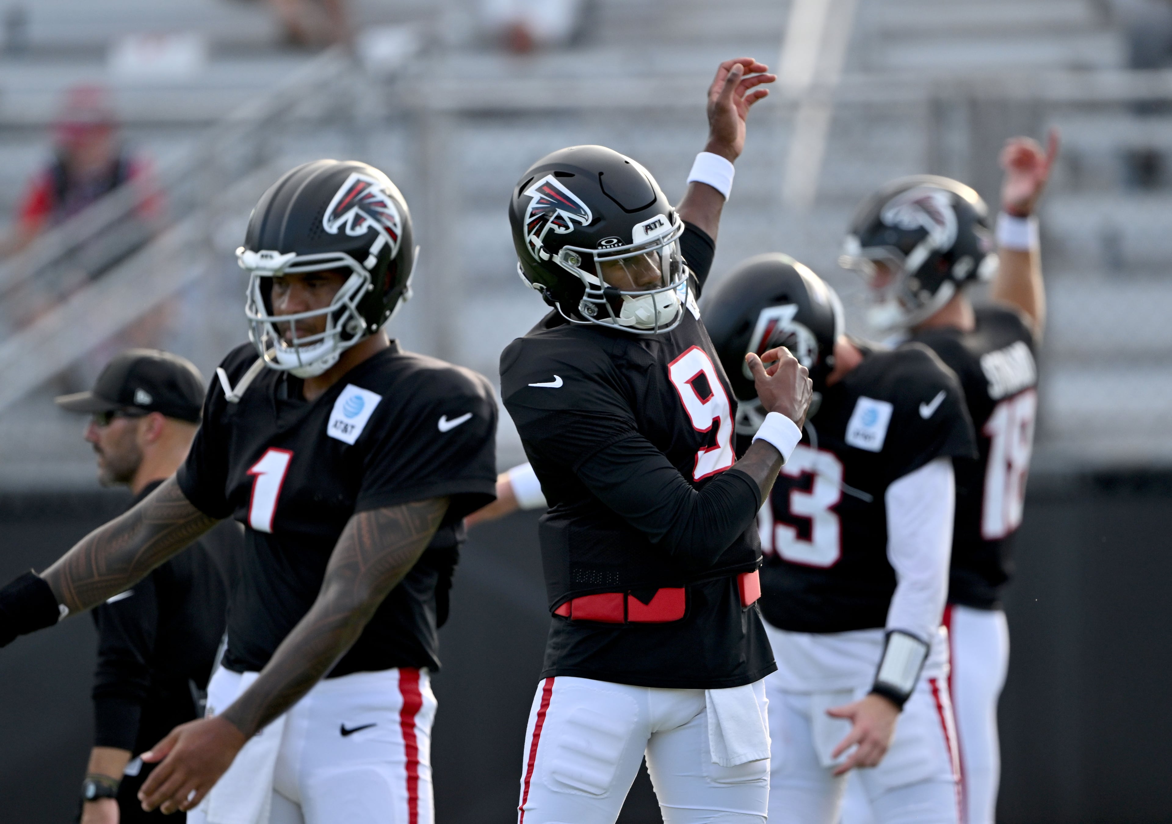 Falcons quarterbacks, from left, Tua Tagovailoa, Michael Penix Jr., Cooper Rush and Jack Strand warm up during "Saturday Night Lights" practice Saturday, Aug. 8, 2026, at Lanier High School in Sugar Hill. (Hyosub Shin/AJC)