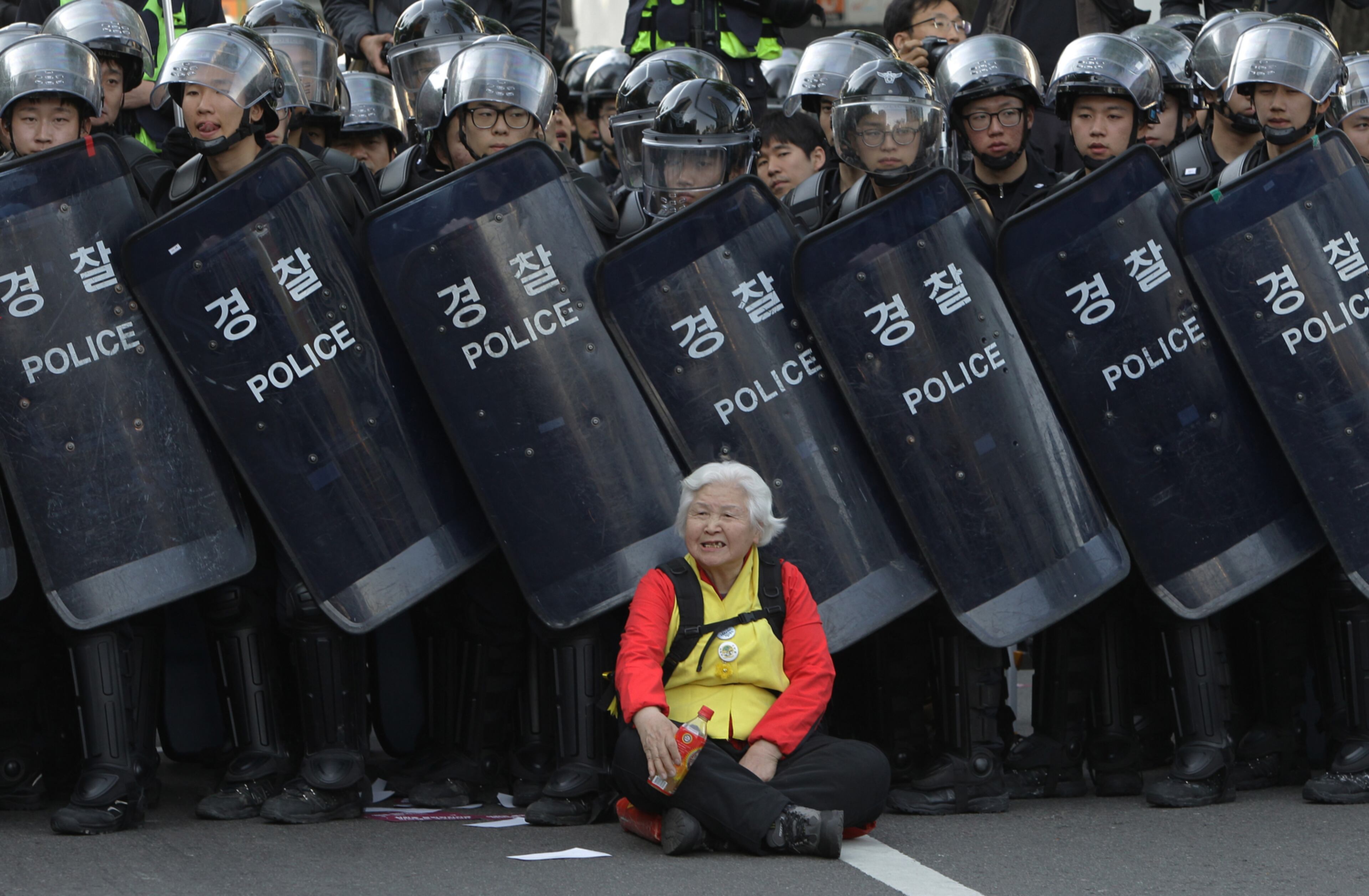 ANTI-GOVERNMENT PROTEST-SEOUL, SOUTH KOREA - APRIL 24: A woman sits in front of riot police blocking the road to protect protesters during the anti-government protest on April 24, 2015 in Seoul, South Korea. Korean Confederation of Trade Unions (KCTU) went on a general strike in protest against the South Korean government's policy, including reformation of the labor market and public pension system. The rally was also joined by other civic groups in Seoul and families of Sewol accident victims. (Photo by Chung Sung-Jun/Getty Images) *** BESTPIX ***