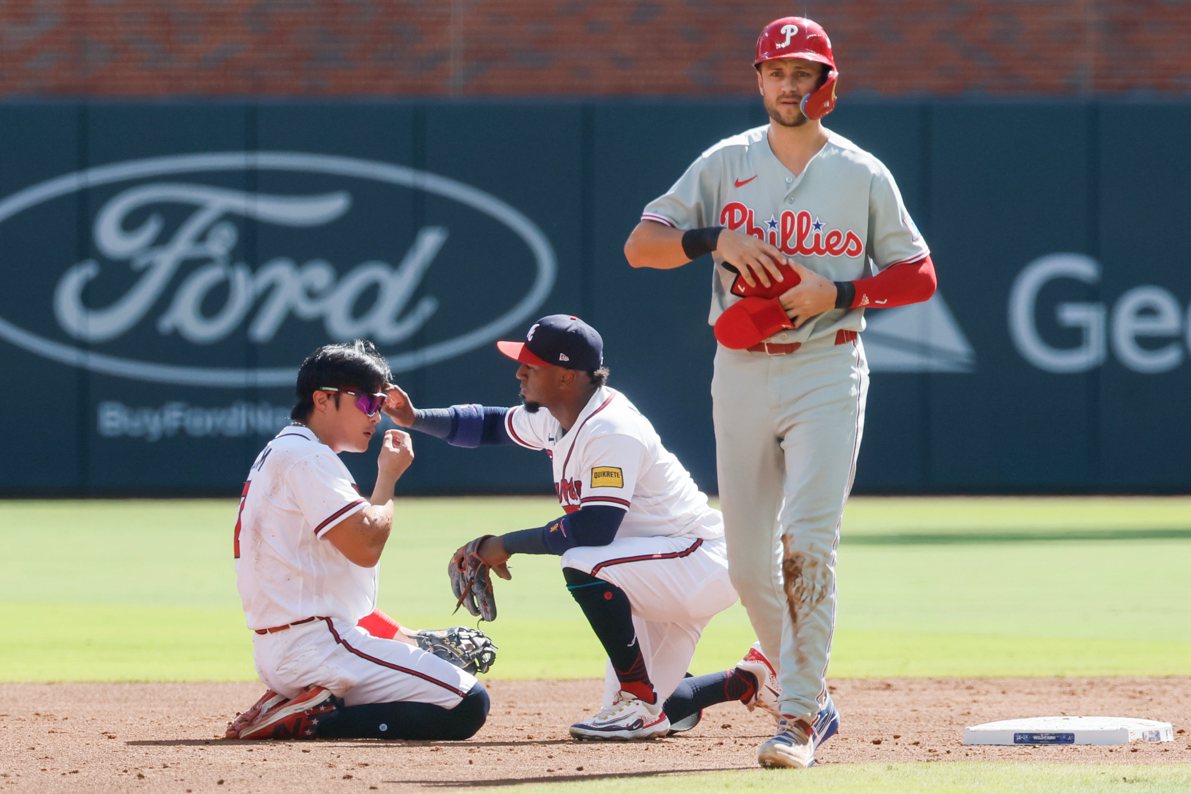 Atlanta Braves second baseman Ozzie Albies, center, checks on Atlanta Braves shortstop Ha-Seong Kim, left, after a collision with Philadelphia Phillies' Trea Turner, right, while getting tagged out on a steal attempt at second base during the third inning of Game 1 of a MLB National League Wild Card playoff series between the Atlanta Braves and the Philadelphia Phillies, Tuesday, Sept. 29, 2026, in Atlanta. (Miguel Martinez/AJC)