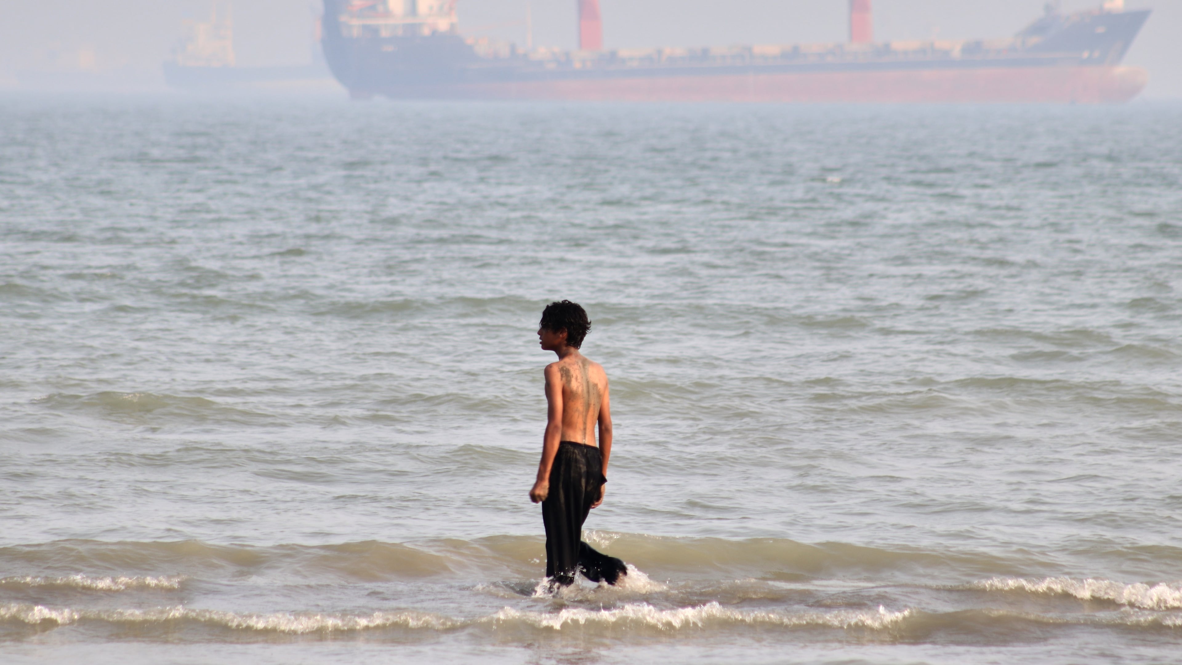 A boy walks on shallow water as commercial vessels are anchored in the Strait of Hormuz off Bandar Abbas, Iran, Monday, Aug. 31, 2026. (Razieh Poudat/ISNA via AP)