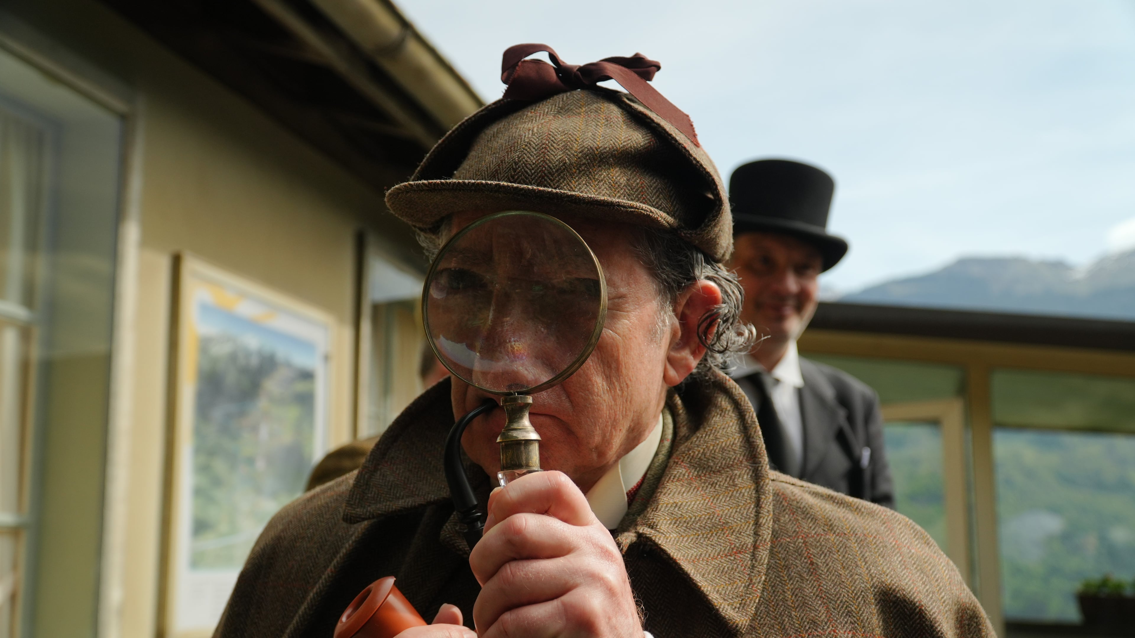 Philip Porter, playing Sherlock Holmes, looking through a magnifying glass during an event recreating the fateful confrontation between Sherlock Holmes and Professor Moriarty by the members of the Sherlock Holmes Society of London, at the Reichenbach Falls, Switzerland, May 3, 2026. (AP Photo/Niccolo Lupone, Pool)