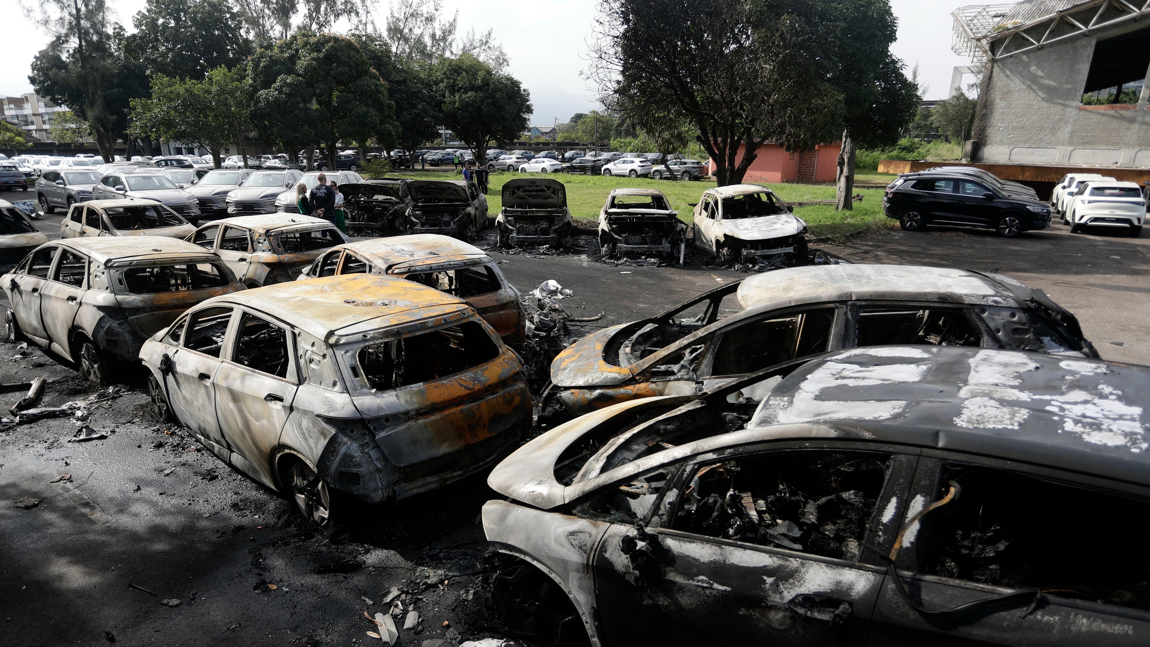 Burned vehicles fill a car dealership parking lot where, according to police, two helicopters collided in midair and crashed in Rio de Janeiro, Brazil, Sunday, June 14, 2026. (AP Photo/Bruna Prado)