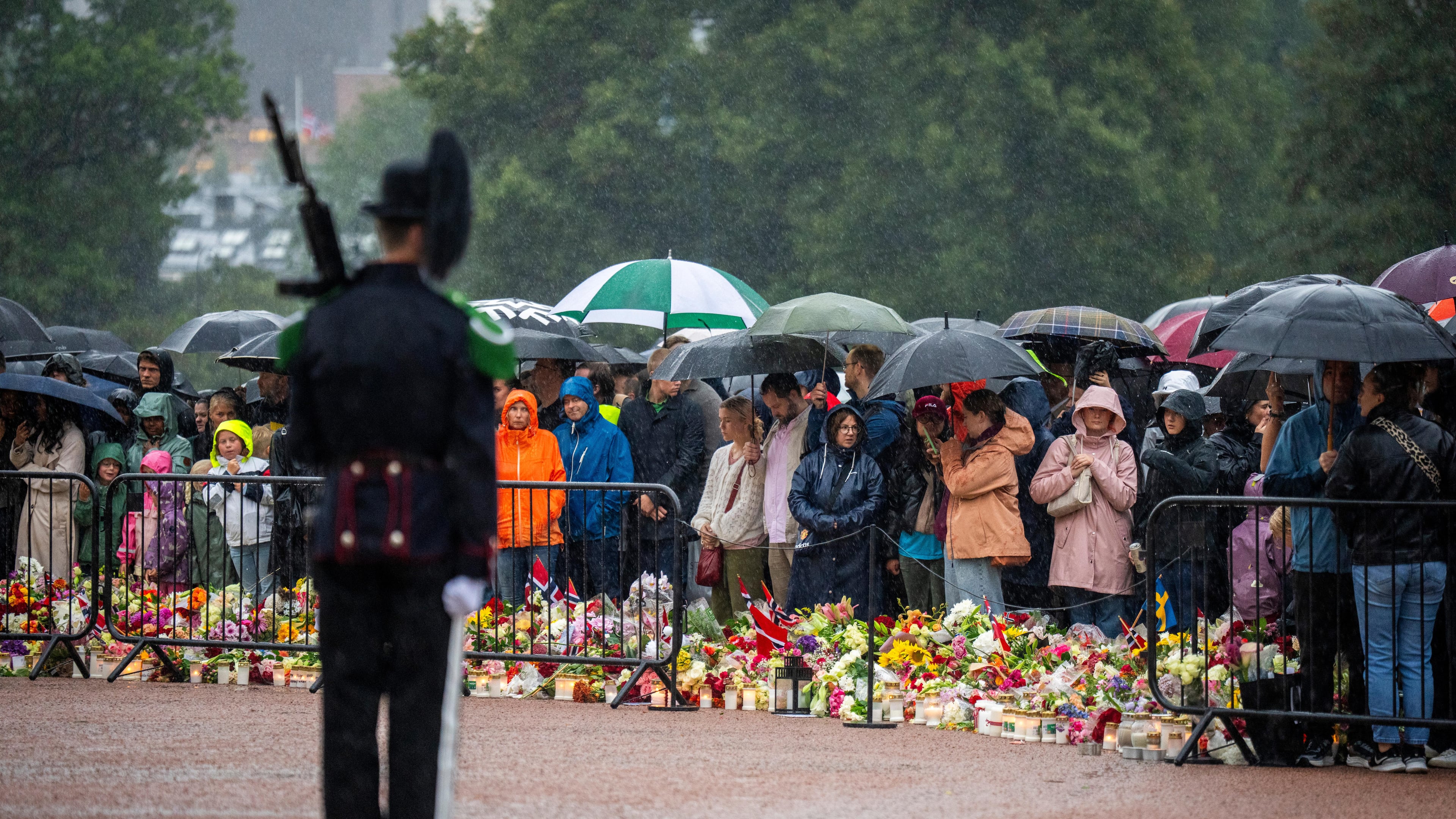Mourners gather in the pouring rain to watch as King Harald V's remains arrive to the Royal Palace in Oslo, Norway, Friday, Aug. 28, 2026. (Heiko Junge/NTB via AP)